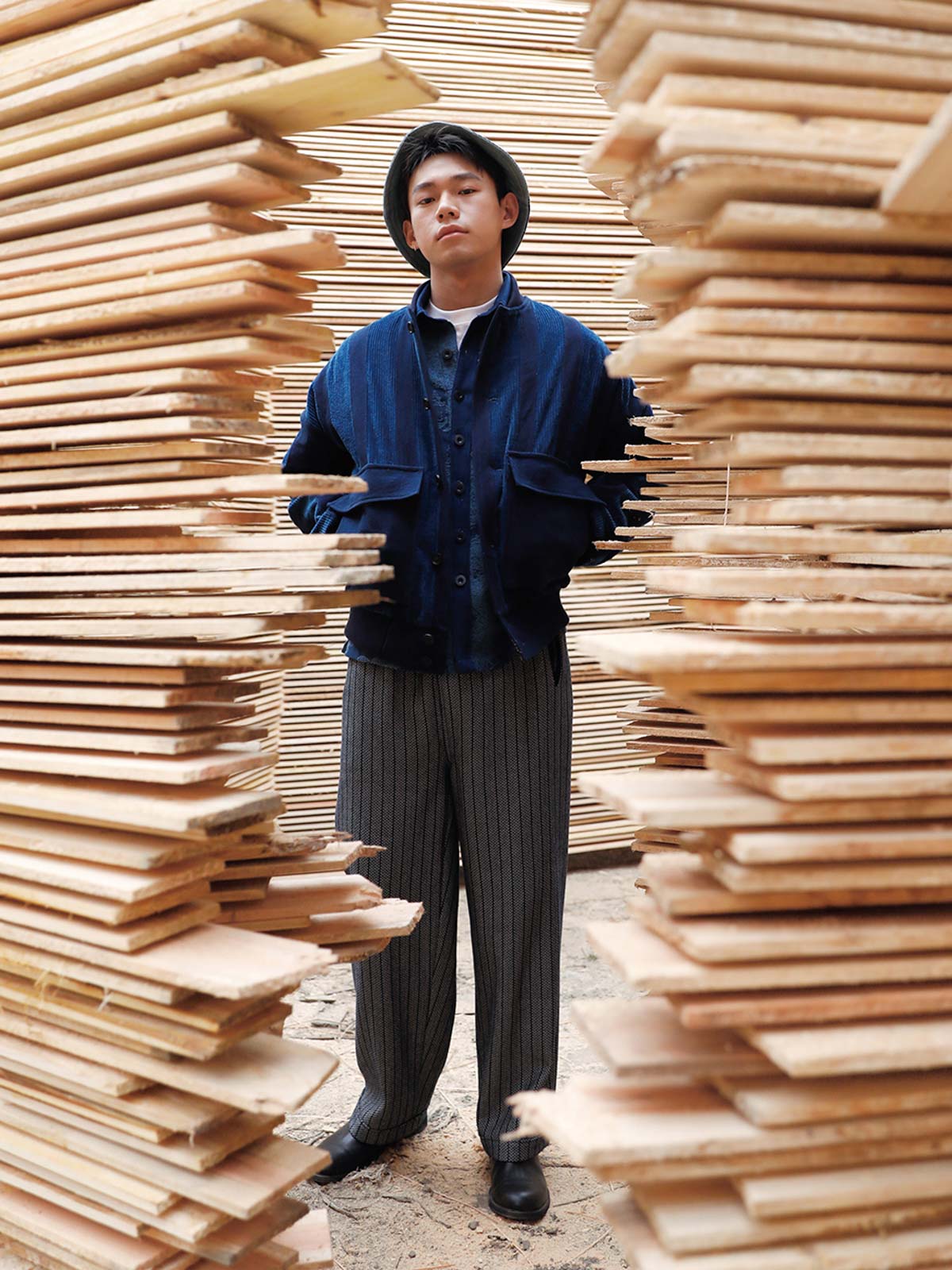 詳細画像: 藍染めストライプと多機能ポケットのディテール画像。ダイヤ柄キルティング加工の中綿が見える耐久性と保温性の高い仕上がり。
モデル画像: モデルが着用する藍染めとストライプパッチワークの民族風スタンドカラージャケット。スポーティーな袖口とゆったりとしたシルエットが映えるコーディネート。