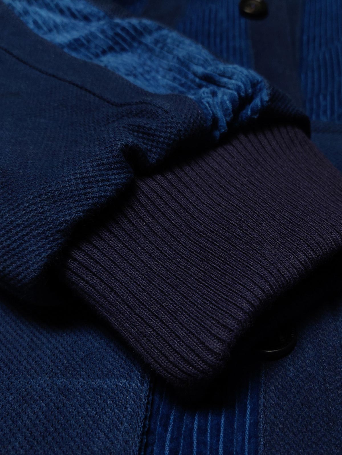 製品画像: 藍染めストライプのコーデュロイスタンドカラージャケット全体像。民族風パッチワークデザインで、太畝のコーデュロイが秋冬に適した温かみを表現。
詳細画像: 藍染めストライプと多機能ポケットのディテール画像。ダイヤ柄キルティング加工の中綿が見える耐久性と保温性の高い仕上がり。