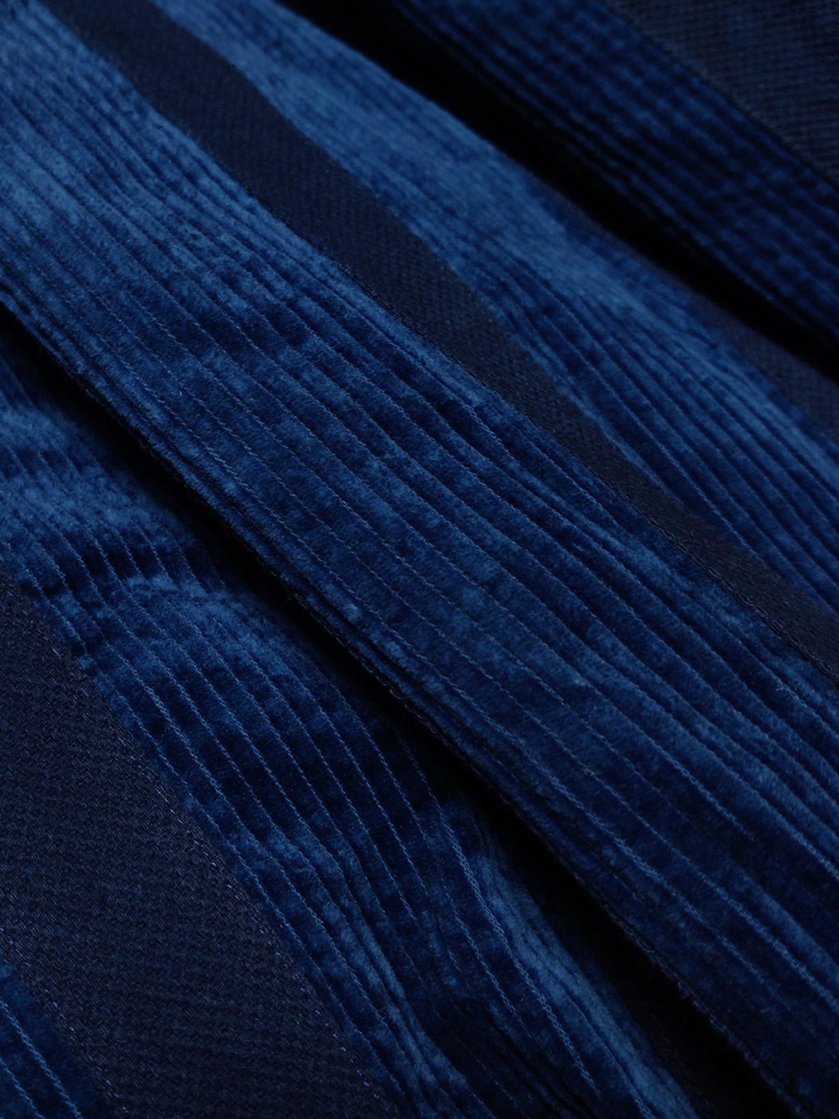 製品画像: 藍染めストライプのコーデュロイスタンドカラージャケット全体像。民族風パッチワークデザインで、太畝のコーデュロイが秋冬に適した温かみを表現。
詳細画像: 藍染めストライプと多機能ポケットのディテール画像。ダイヤ柄キルティング加工の中綿が見える耐久性と保温性の高い仕上がり。