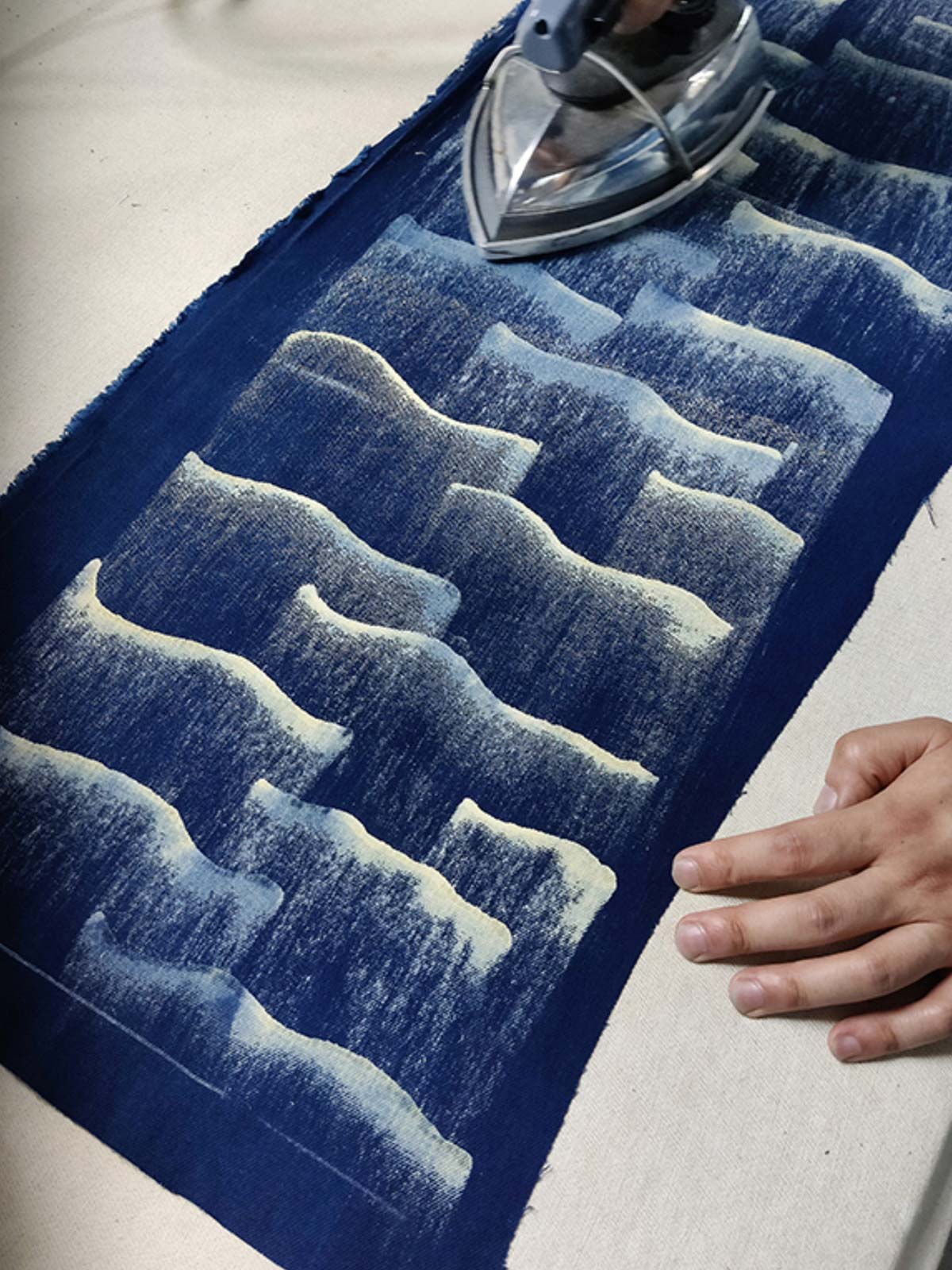 製品画像: 雲海柄藍染めバイカージャケット全体表示。ジャカードコットン素材と独特な抜染技法で、都会と自然が交わるデザイン。
詳細画像: 雲海抜染柄と伸縮性のある裾デザインのディテール表示。テクスチャーの深みと実用的な裾仕上げが際立つディテール。