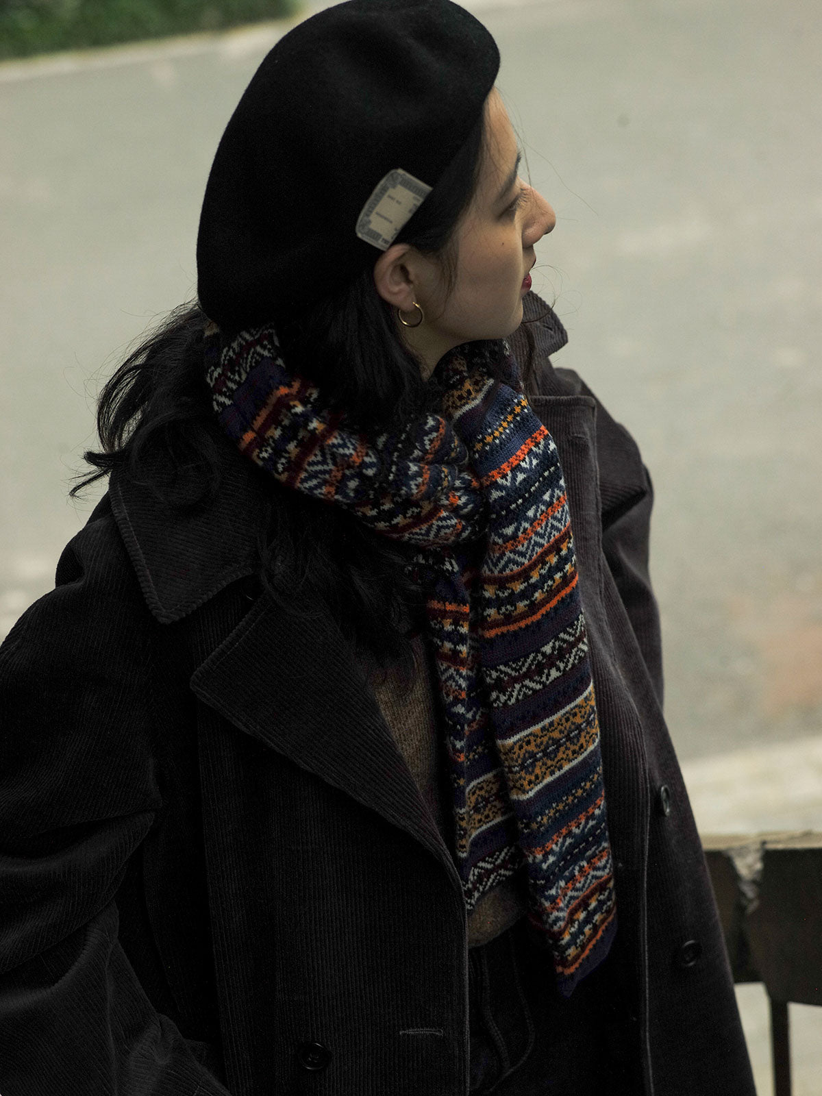 詳細画像:マフラーの織り目とフェアアイランド柄のディテールが鮮明に描かれており、シェトランドウール特有の柔らかな質感と耐久性が伝わります。染色技術にこだわったカラフルな糸が、アクセントとなる美しいデザインを際立たせています。
モデル画像:シェトランドウールのフェアアイランド柄マフラーを着用したモデルが、ヴィンテージ感のあるスタイルでコーディネートしています。マフラーの柔らかさと温かさが際立ち、日常的なカジュアルスタイルにもぴったりのアイテムであることを示しています。