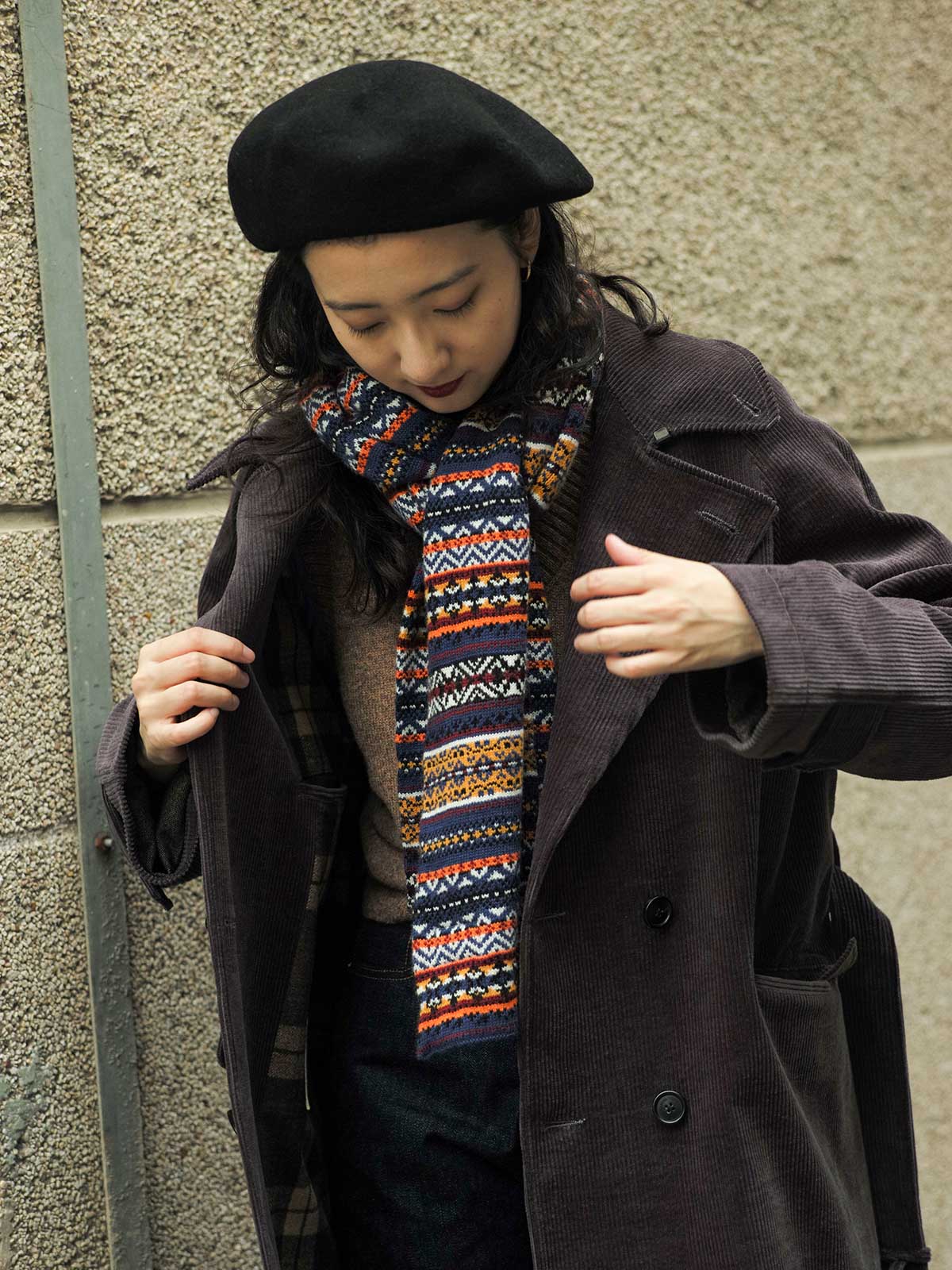 詳細画像:マフラーの織り目とフェアアイランド柄のディテールが鮮明に描かれており、シェトランドウール特有の柔らかな質感と耐久性が伝わります。染色技術にこだわったカラフルな糸が、アクセントとなる美しいデザインを際立たせています。
モデル画像:シェトランドウールのフェアアイランド柄マフラーを着用したモデルが、ヴィンテージ感のあるスタイルでコーディネートしています。マフラーの柔らかさと温かさが際立ち、日常的なカジュアルスタイルにもぴったりのアイテムであることを示しています。