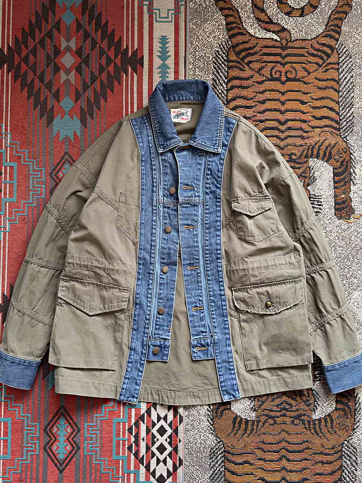 製品画像:
マルチ素材パッチワークデニムジャケットの全体画像。ミリタリーグリーンとデニム素材のパッチワークが特徴的で、ウォッシュ加工によりヴィンテージ感とトレンド感を兼ね備えています。
詳細画像:
ジャケットのパッチワークデザイン、ウォッシュ加工によるユーズド感、ディテールにこだわったボタンとジッパー部分。