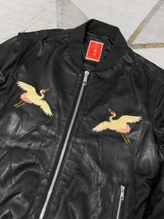 製品画像: 横須賀鶴図刺繍 羊革ジャケット全体画像、吉祥の象徴である「鶴図」刺繍と上質な輸入羊革のデザイン
詳細画像: 横須賀の伝統技法を用いた鶴、松、雲の刺繍ディテール、立体感ある精巧な工芸