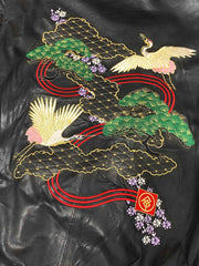 製品画像: 横須賀鶴図刺繍 羊革ジャケット全体画像、吉祥の象徴である「鶴図」刺繍と上質な輸入羊革のデザイン
詳細画像: 横須賀の伝統技法を用いた鶴、松、雲の刺繍ディテール、立体感ある精巧な工芸