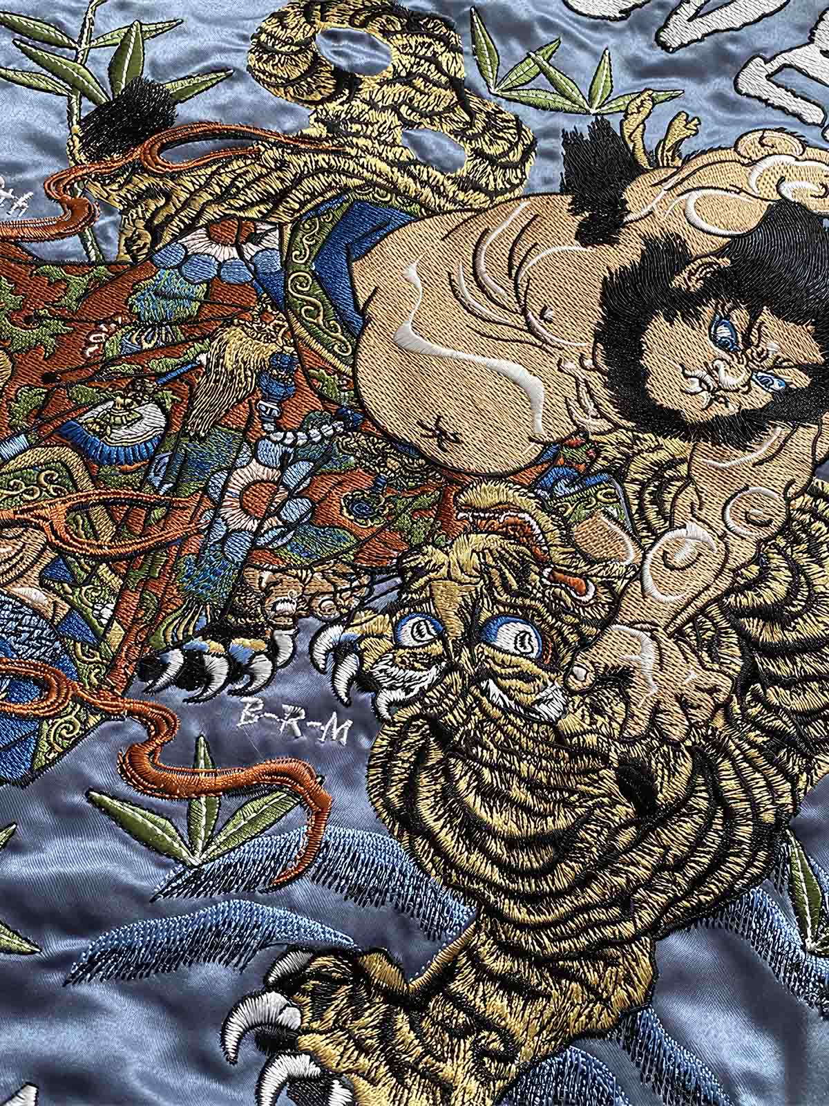 製品画像: リバーシブル 刺繍 横須賀 ベルベット ジャケット全体画像、伝統的な日本の横須賀刺繍とヴィンテージデザイン
詳細画像: 武松の虎退治と鬼若丸の鯉退治の刺繍ディテール、横須賀刺繍の高度な技法と精緻な表現