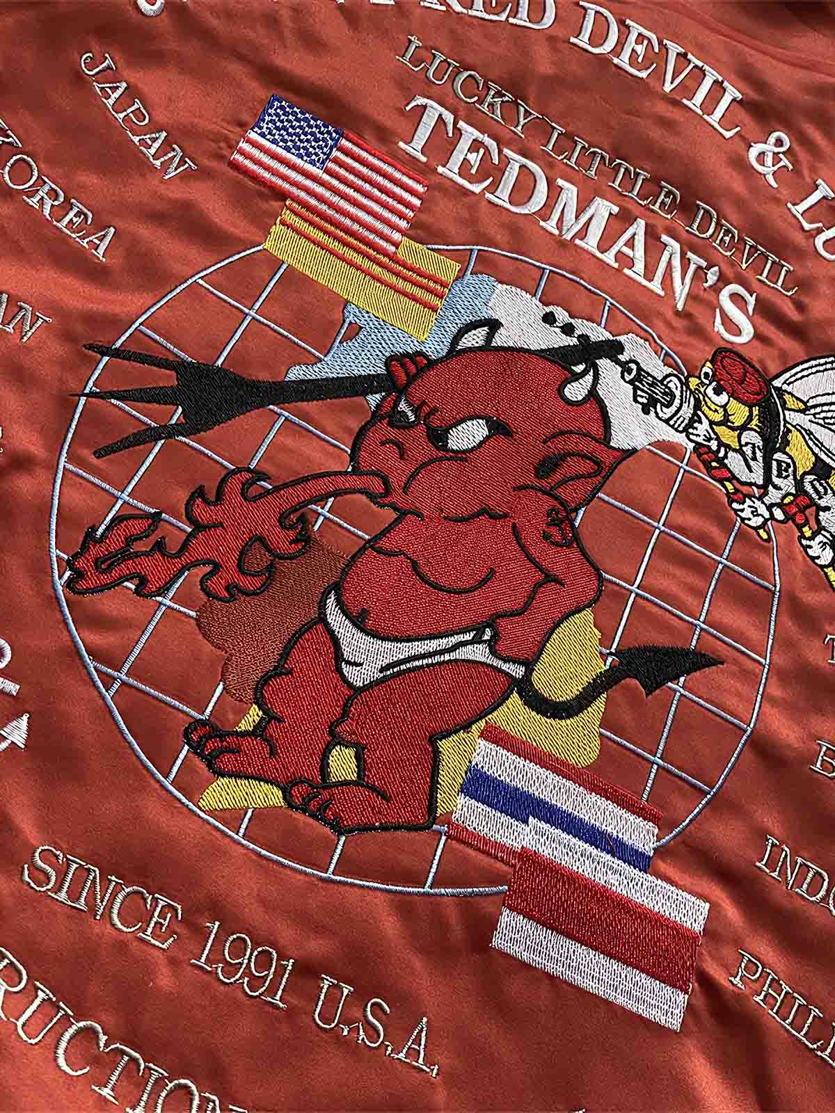 製品画像: リバーシブル 刺繍 横須賀 テッドマン 着物ギタリスト ジャケット全体画像、アメリカ文化と日本伝統を融合したデザイン
詳細画像: テッドマン(幸运の赤鬼)と着物ギタリストの刺繍ディテール、横須賀刺繍の芸術的な美しさと細部へのこだわり