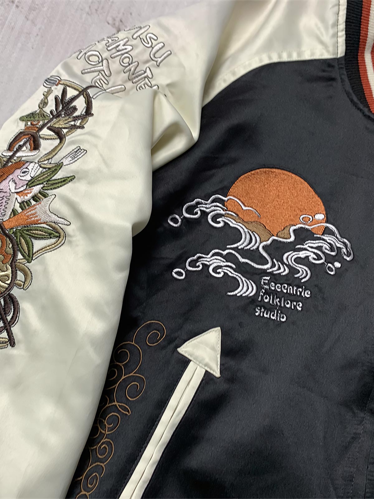 製品画像: リバーシブル シルク刺繍 横須賀 「Fortune Favors the Bold」(幸運は勇者を好む) ジャケットの全体画像、日本文化とヴィンテージスタイルの融合
詳細画像: 「Fortune Favors the Bold」(幸運は勇者を好む)の文字と鷹と蛇のトーテム、七福神の刺繍ディテール、横須賀刺繍の精緻な技法