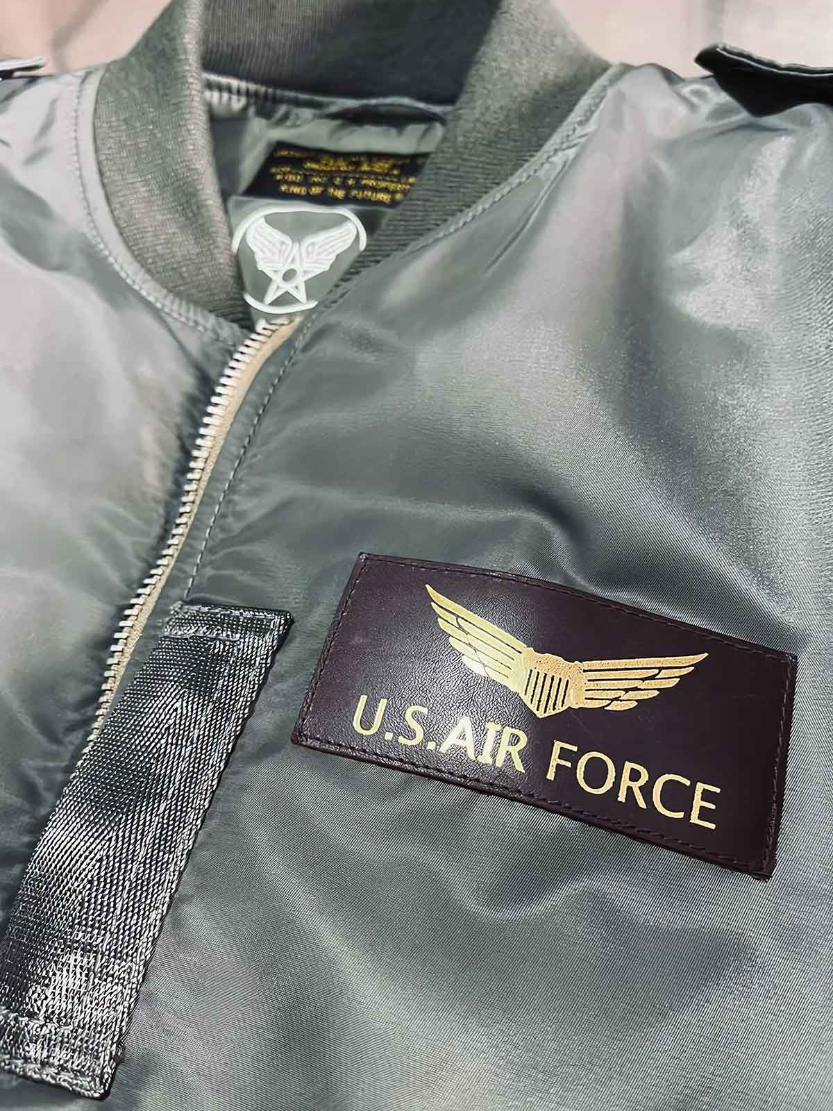 製品画像: L2-Bヴィンテージフライトジャケットの全体画像、ミリタリーグリーンとキャプテンランクの肩章が特徴のデザイン
詳細画像: 背面のポスター調デザインとキャプテンランク肩章のディテール、1940年代風のミリタリースタイル