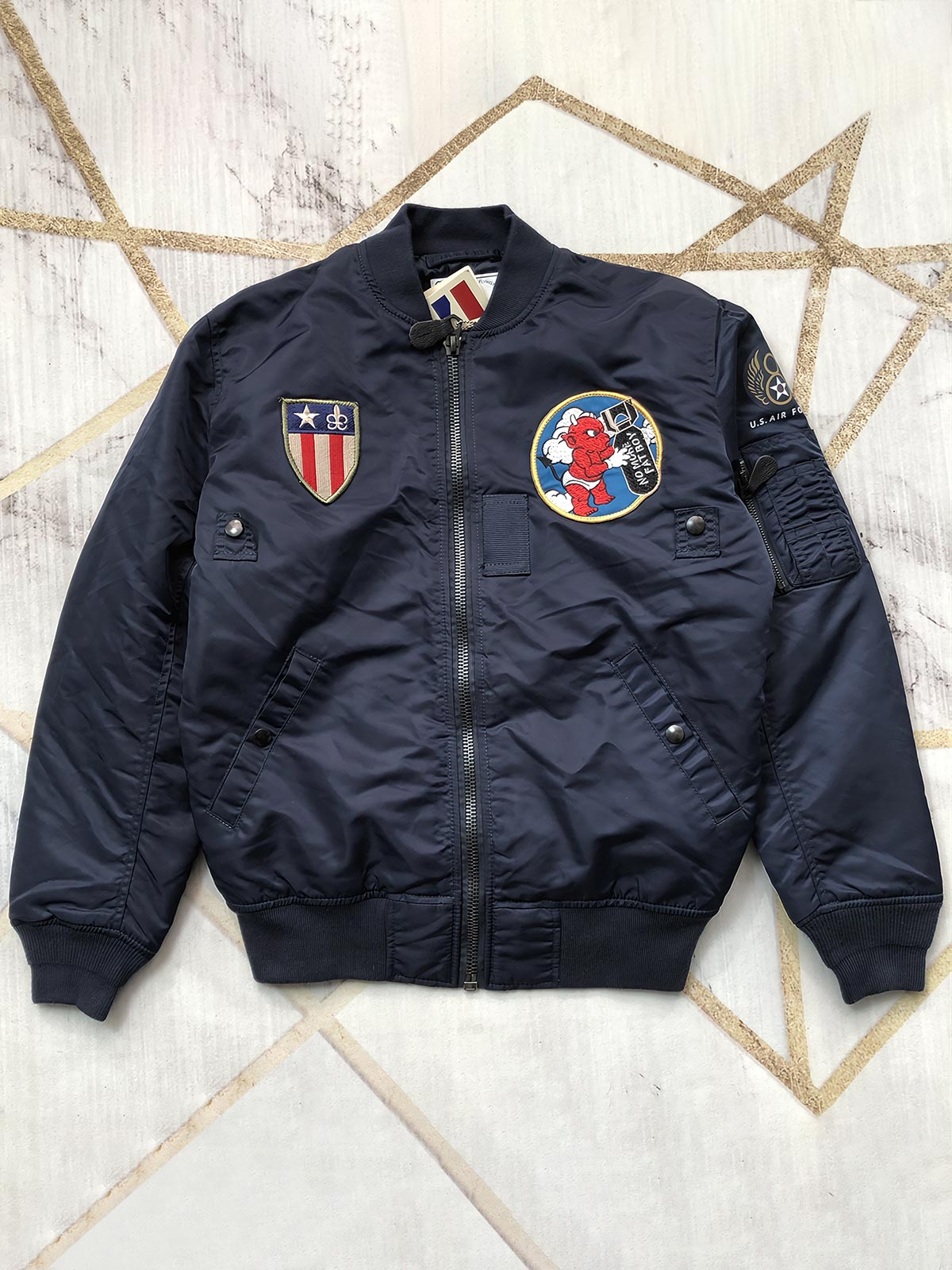 製品画像: テッドマン刺繍MA-1飛行ジャケットの全体画像、ヴィンテージアメリカンミリタリースタイルが特徴
詳細画像: ジャケット背面のテッドマン刺繍と「WE'LL GIVE 'EM HELL!」スローガンのディテール