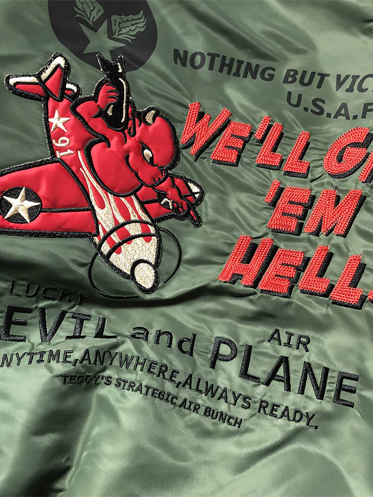 製品画像: テッドマン刺繍MA-1飛行ジャケットの全体画像、ヴィンテージアメリカンミリタリースタイルが特徴
詳細画像: ジャケット背面のテッドマン刺繍と「WE'LL GIVE 'EM HELL!」スローガンのディテール