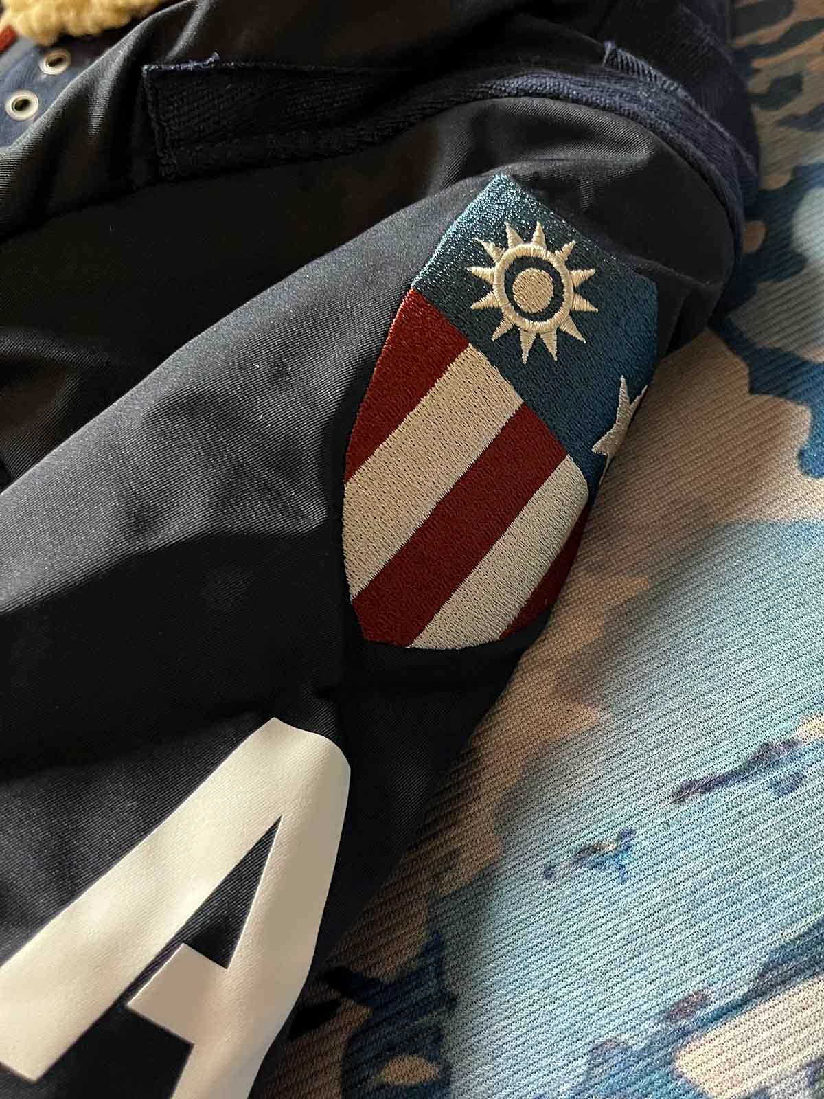 製品画像: 第74戦闘飛行中隊 B3 フライトジャケットの全体画像、シープスキン裏地とクラシックなミリタリースタイル
詳細画像: 背面の「74th FIGHTER SQ.」ロゴとアメリカ空軍マークの刺繍ディテール