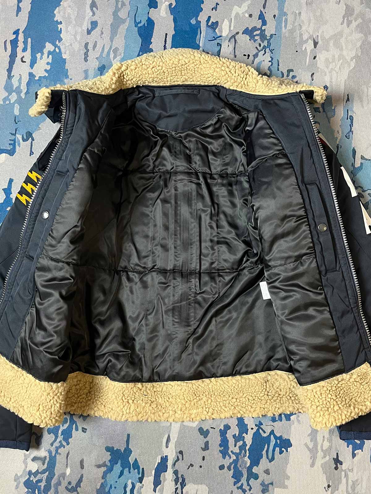 製品画像: 第74戦闘飛行中隊 B3 フライトジャケットの全体画像、シープスキン裏地とクラシックなミリタリースタイル
詳細画像: 背面の「74th FIGHTER SQ.」ロゴとアメリカ空軍マークの刺繍ディテール