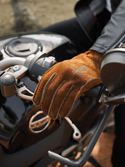 詳細画像
グローブのディテールと素材感アップ。マットレザーを使用した手袋の細部が強調されており、特にダブルステッチや鷲の目のデザインが、製品の耐久性と独特な個性を引き立てています。手に馴染む柔らかな質感や、ヴィンテージの風合いが美しく表現されています。
モデル画像
モデルがマットレザーのバイカーズグローブを着用したライディングスタイル。バイカーズグローブのデザインやフィット感が実際の使用シーンでどのように活かされるかがわかります。ライダーにとって必要な機能性とファッション性を兼ね備えたアイテムで、アウトドアや日常のライディングに最適です。