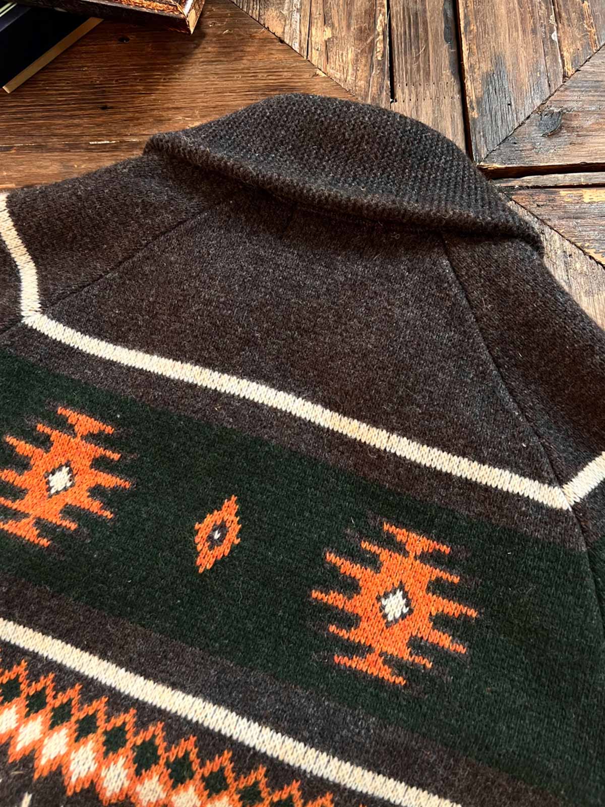 製品画像
ナバホ柄が特徴のオープンカラー(開襟)デザインのウール混紡カーディガン。民族幾何学模様が取り入れられたアメカジレトロスタイルで、秋冬のコーディネートに最適。厚手のウール混紡素材が保温性と快適さを提供する正面全体像。
詳細画像
ナバホ柄カーディガンのジッパーディテールとウール混紡素材の質感を特写。幾何学模様の編み込みデザインが民族風の魅力を強調し、耐久性と柔らかさを兼ね備えた生地の特徴を示すクローズアップ画像。