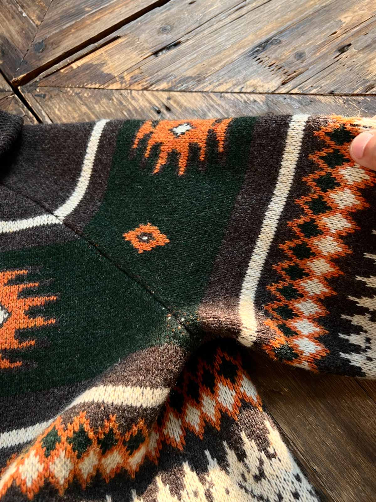 製品画像
ナバホ柄が特徴のオープンカラー(開襟)デザインのウール混紡カーディガン。民族幾何学模様が取り入れられたアメカジレトロスタイルで、秋冬のコーディネートに最適。厚手のウール混紡素材が保温性と快適さを提供する正面全体像。
詳細画像
ナバホ柄カーディガンのジッパーディテールとウール混紡素材の質感を特写。幾何学模様の編み込みデザインが民族風の魅力を強調し、耐久性と柔らかさを兼ね備えた生地の特徴を示すクローズアップ画像。