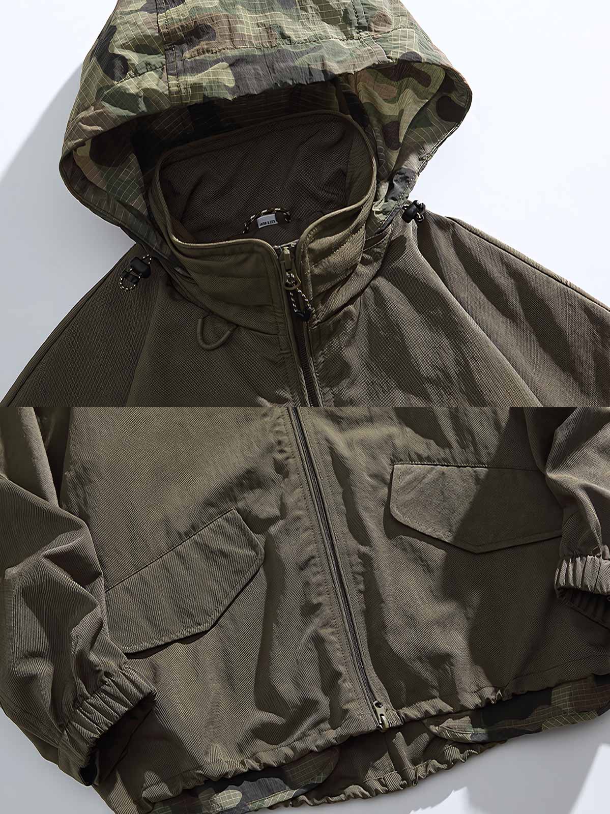 製品画像
アウトドア機能性 速乾 防風 撥水 フード付きジャケットの正面全体像。高密度ナイロンオックスフォードジャカード生地を使用し、三防(速乾、防風、撥水)性能を兼ね備えたデザイン。調整可能なフード付きで、都市からアウトドアまで幅広く活躍。
詳細画像
フード付きジャケットの水平に配置されたポケット部分を特写。フラップ付きポケットの内部には隠しマグネットボタンが内蔵されており、安全性と収納性を向上。高密度ナイロン素材の撥水加工とディテールが際立つ特写画像。