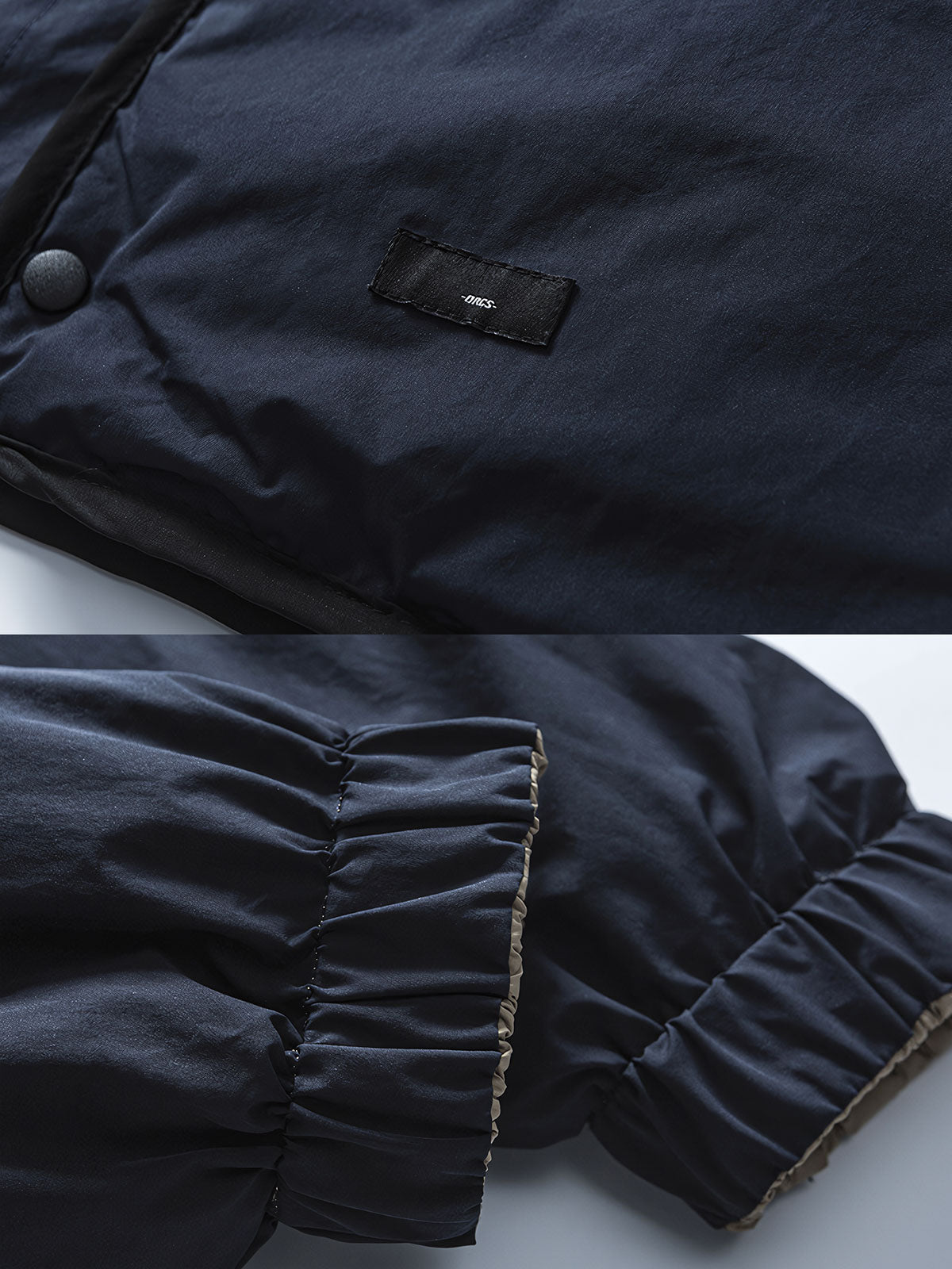 製品画像: リバーシブル撥水・撥油・防汚軽量ダウンジャケットの全体イメージ画像。ホワイトダックダウン90%を使用した中綿と、特別なテフロンコーティングを施した外層が特徴的。グレーベージュとネイビーの両面デザインで、アウトドアから日常コーデまで幅広く活用可能。
詳細画像: 撥水・撥油・防汚加工が施された外層と、軽量ホワイトダックダウン中綿をクローズアップしたディテール画像。耐久性と保温性を兼ね備えた素材が際立つ。