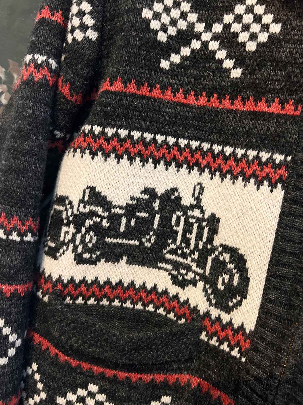 製品画像: ヴィンテージバイカージャカードウールカーディガン全体イメージ画像。バイクモチーフのジャカード織りと赤・黒・白のクラシックな配色が特徴で、自由とヴィンテージ感を象徴するデザイン。秋冬の重ね着スタイルに最適。
詳細画像: ジャカード織りで描かれたバイクモチーフと、クラシックなダブルジップディテールをクローズアップした画像。暖かいウール素材と細部へのこだわりが際立つ。
