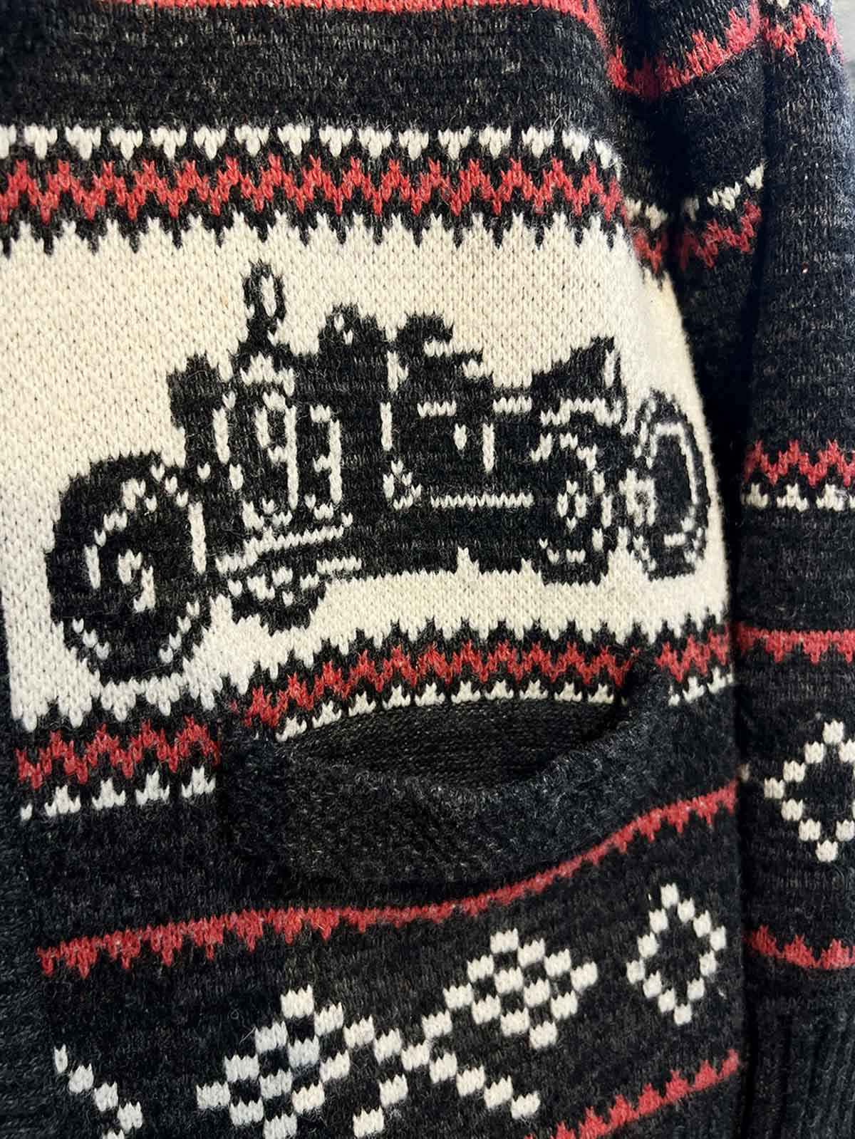 製品画像: ヴィンテージバイカージャカードウールカーディガン全体イメージ画像。バイクモチーフのジャカード織りと赤・黒・白のクラシックな配色が特徴で、自由とヴィンテージ感を象徴するデザイン。秋冬の重ね着スタイルに最適。
詳細画像: ジャカード織りで描かれたバイクモチーフと、クラシックなダブルジップディテールをクローズアップした画像。暖かいウール素材と細部へのこだわりが際立つ。