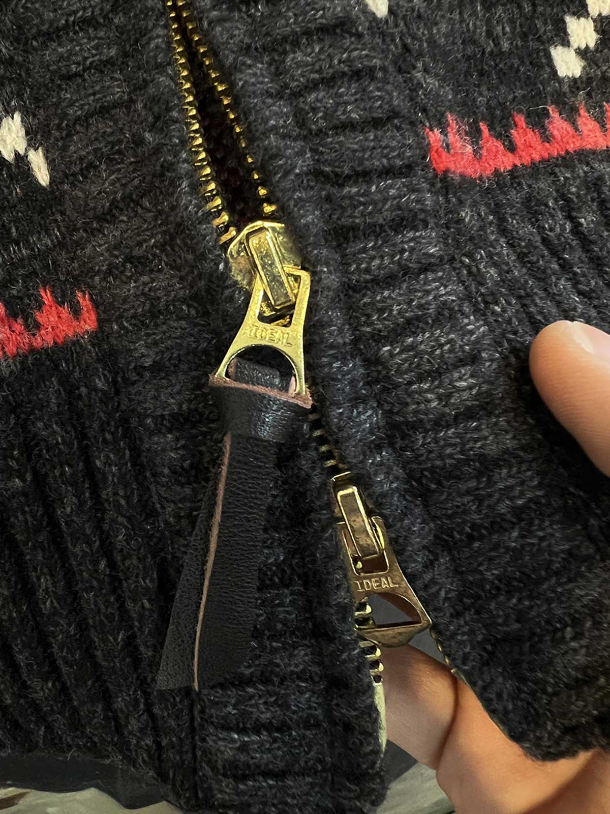 製品画像: ヴィンテージバイカージャカードウールカーディガン全体イメージ画像。バイクモチーフのジャカード織りと赤・黒・白のクラシックな配色が特徴で、自由とヴィンテージ感を象徴するデザイン。秋冬の重ね着スタイルに最適。
詳細画像: ジャカード織りで描かれたバイクモチーフと、クラシックなダブルジップディテールをクローズアップした画像。暖かいウール素材と細部へのこだわりが際立つ。