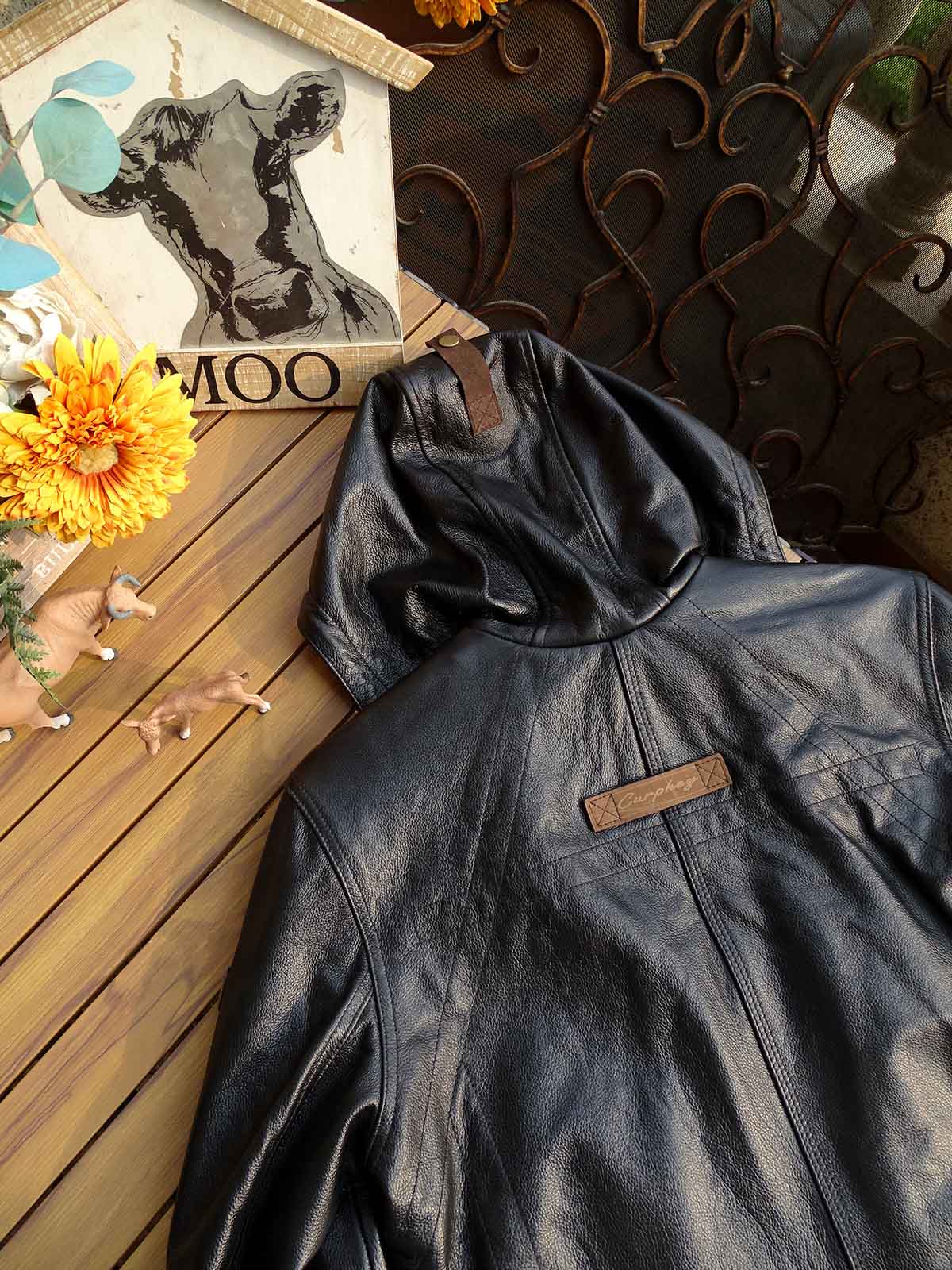 製品画像: 9ポケットフィールドフード付きフルグレインレザージャケット全体イメージ画像。黒いシボ加工レザーとヴィンテージ感漂うオイル仕上げのスエードディテールが特徴で、アウトドアやバイクライドにも適した多機能デザイン。
詳細画像: YKKアンティークブロンズジッパーとオイルドスエードレザーの補強ディテールをクローズアップした画像。耐久性とクラシックな風合いが際立つ仕上がり。