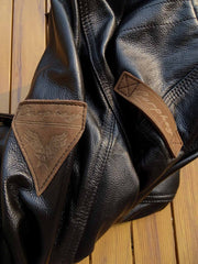 製品画像: 9ポケットフィールドフード付きフルグレインレザージャケット全体イメージ画像。黒いシボ加工レザーとヴィンテージ感漂うオイル仕上げのスエードディテールが特徴で、アウトドアやバイクライドにも適した多機能デザイン。
詳細画像: YKKアンティークブロンズジッパーとオイルドスエードレザーの補強ディテールをクローズアップした画像。耐久性とクラシックな風合いが際立つ仕上がり。