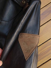 製品画像: 9ポケットフィールドフード付きフルグレインレザージャケット全体イメージ画像。黒いシボ加工レザーとヴィンテージ感漂うオイル仕上げのスエードディテールが特徴で、アウトドアやバイクライドにも適した多機能デザイン。
詳細画像: YKKアンティークブロンズジッパーとオイルドスエードレザーの補強ディテールをクローズアップした画像。耐久性とクラシックな風合いが際立つ仕上がり。