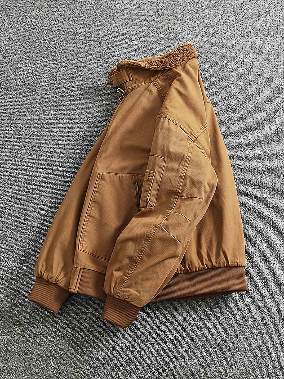 製品画像:
"水洗い加工を施したシープスキンライニング付きフライトジャケットの全体図。クラシックなアメカジスタイル、シープスキンカラーとツイル織りコットンの組み合わせでヴィンテージ感を引き立てたデザイン"
詳細画像:
"シープスキン風ライニングとリブ仕様の裾ディテールをクローズアップした画像。裏地の柔らかさと保温性が際立ち、防風性を兼ね備えたデザインが強調される"