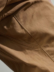 製品画像:紫タグが付いたワーク テーパードパンツの全体像。高品質な純銅YKKジッパーや金属ボタン、そしてしっかりとしたテーパードシルエットが際立ち、スタイリッシュで実用的なデザインが特徴のパンツを全体的に見せる展示画像。
詳細画像:紫タグが強調されたバックルベルトと隠しワークポケットのディテールクローズアップ。バックルベルト部分の調節機能と隠しポケットのディテールが、実用性とデザイン性を兼ね備えた特徴を詳しく見せる画像。