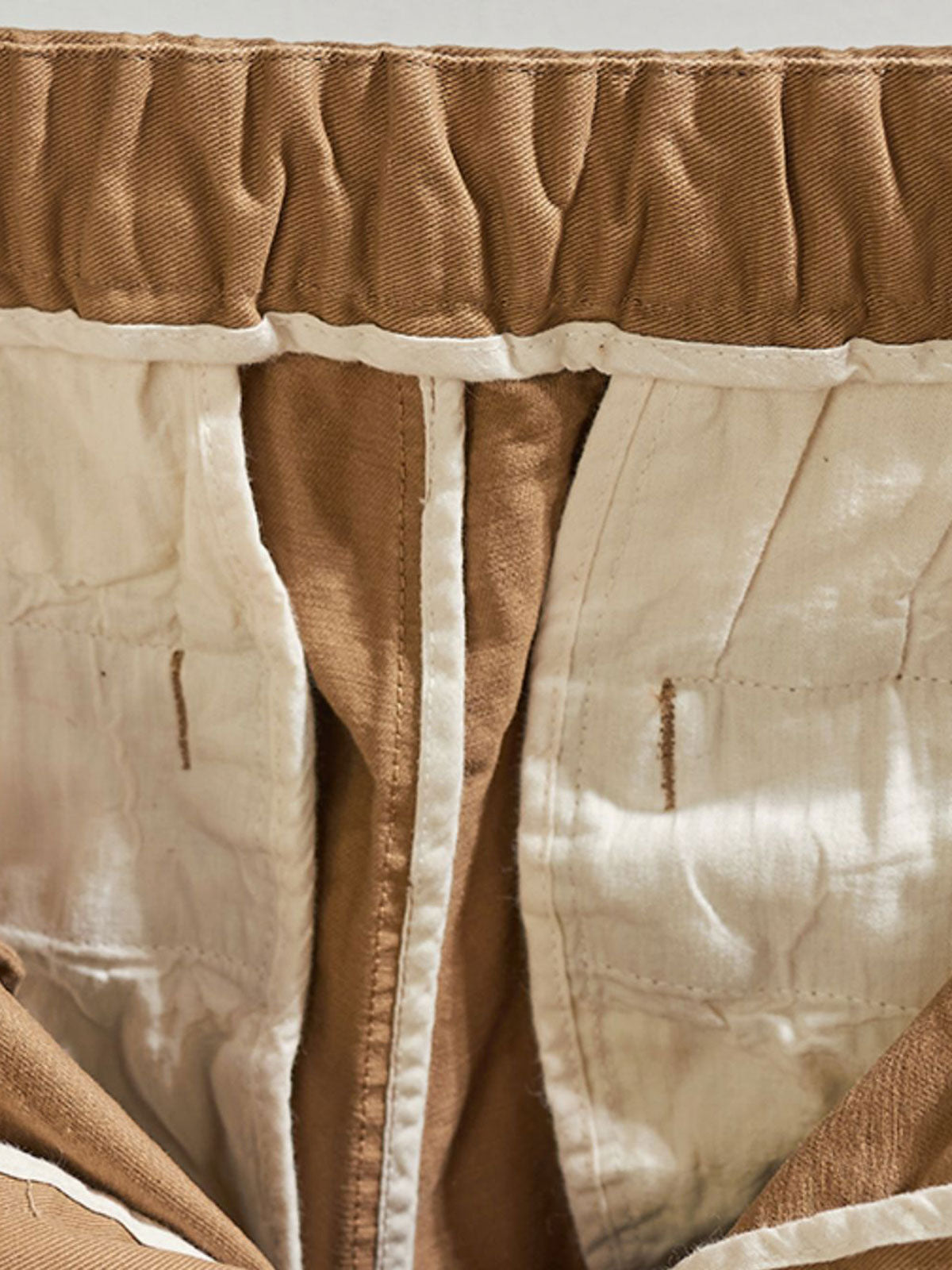 製品画像:紫タグが付いたワーク テーパードパンツの全体像。高品質な純銅YKKジッパーや金属ボタン、そしてしっかりとしたテーパードシルエットが際立ち、スタイリッシュで実用的なデザインが特徴のパンツを全体的に見せる展示画像。
詳細画像:紫タグが強調されたバックルベルトと隠しワークポケットのディテールクローズアップ。バックルベルト部分の調節機能と隠しポケットのディテールが、実用性とデザイン性を兼ね備えた特徴を詳しく見せる画像。