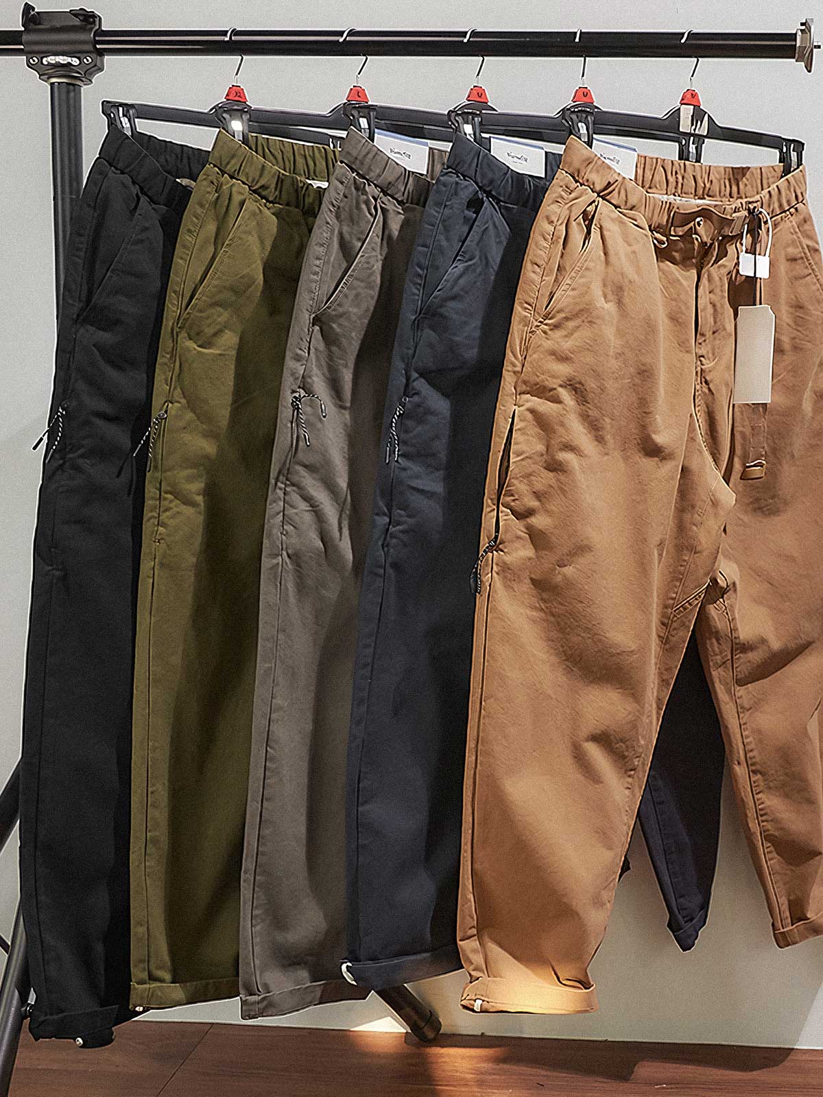 製品画像:紫タグが付いたワーク テーパードパンツの全体像。高品質な純銅YKKジッパーや金属ボタン、そしてしっかりとしたテーパードシルエットが際立ち、スタイリッシュで実用的なデザインが特徴のパンツを全体的に見せる展示画像。
詳細画像:紫タグが強調されたバックルベルトと隠しワークポケットのディテールクローズアップ。バックルベルト部分の調節機能と隠しポケットのディテールが、実用性とデザイン性を兼ね備えた特徴を詳しく見せる画像。