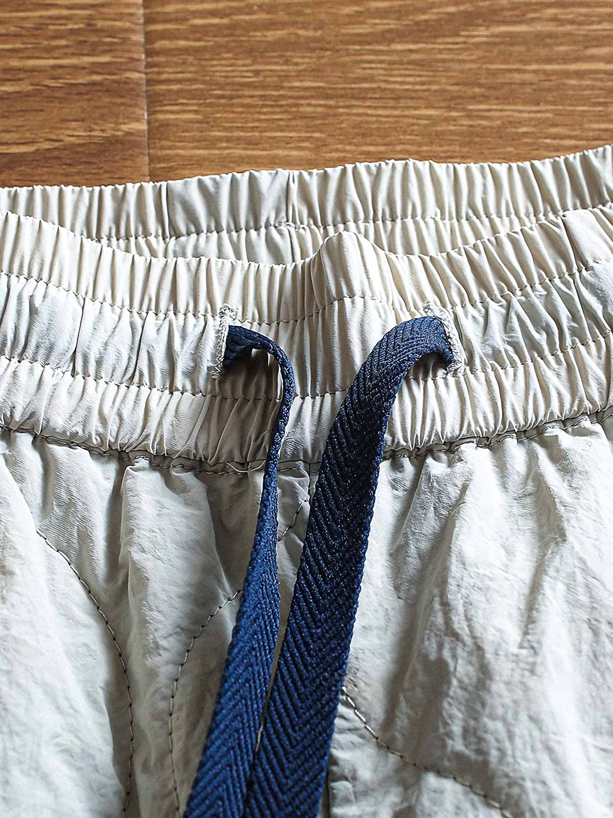 製品画像: 防風・防水機能を備えたキルティング中綿入り保温パンツ全体展示図。冬のアウトドア活動や寒い季節のカジュアルコーディネートに最適な高機能パンツ。
詳細画像: 高反発中綿が使用されたキルティングデザインのディテール。ウエストの伸縮性ゴムとドローコード、裾部分の調節機能で、機能性と快適さを兼ね備えたアウトドアパンツの特徴。