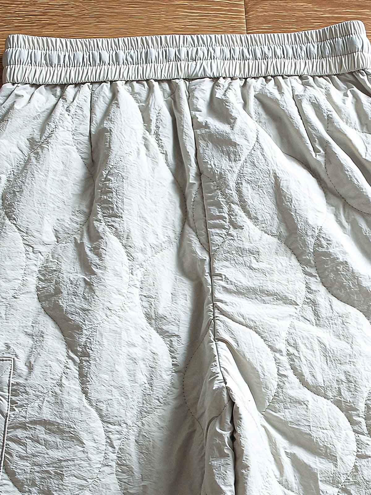 製品画像: 防風・防水機能を備えたキルティング中綿入り保温パンツ全体展示図。冬のアウトドア活動や寒い季節のカジュアルコーディネートに最適な高機能パンツ。
詳細画像: 高反発中綿が使用されたキルティングデザインのディテール。ウエストの伸縮性ゴムとドローコード、裾部分の調節機能で、機能性と快適さを兼ね備えたアウトドアパンツの特徴。