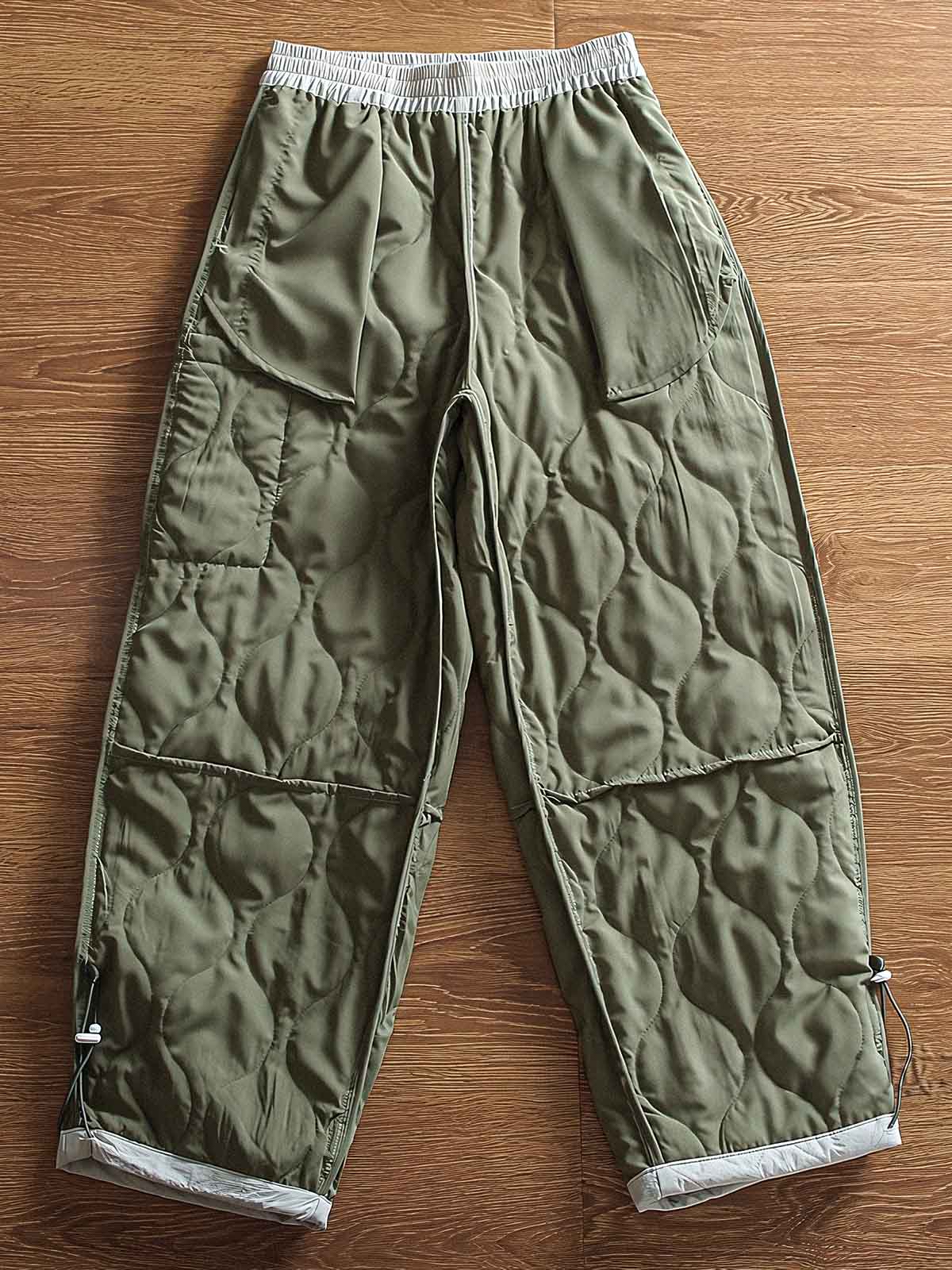 製品画像: 防風・防水機能を備えたキルティング中綿入り保温パンツ全体展示図。冬のアウトドア活動や寒い季節のカジュアルコーディネートに最適な高機能パンツ。
詳細画像: 高反発中綿が使用されたキルティングデザインのディテール。ウエストの伸縮性ゴムとドローコード、裾部分の調節機能で、機能性と快適さを兼ね備えたアウトドアパンツの特徴。