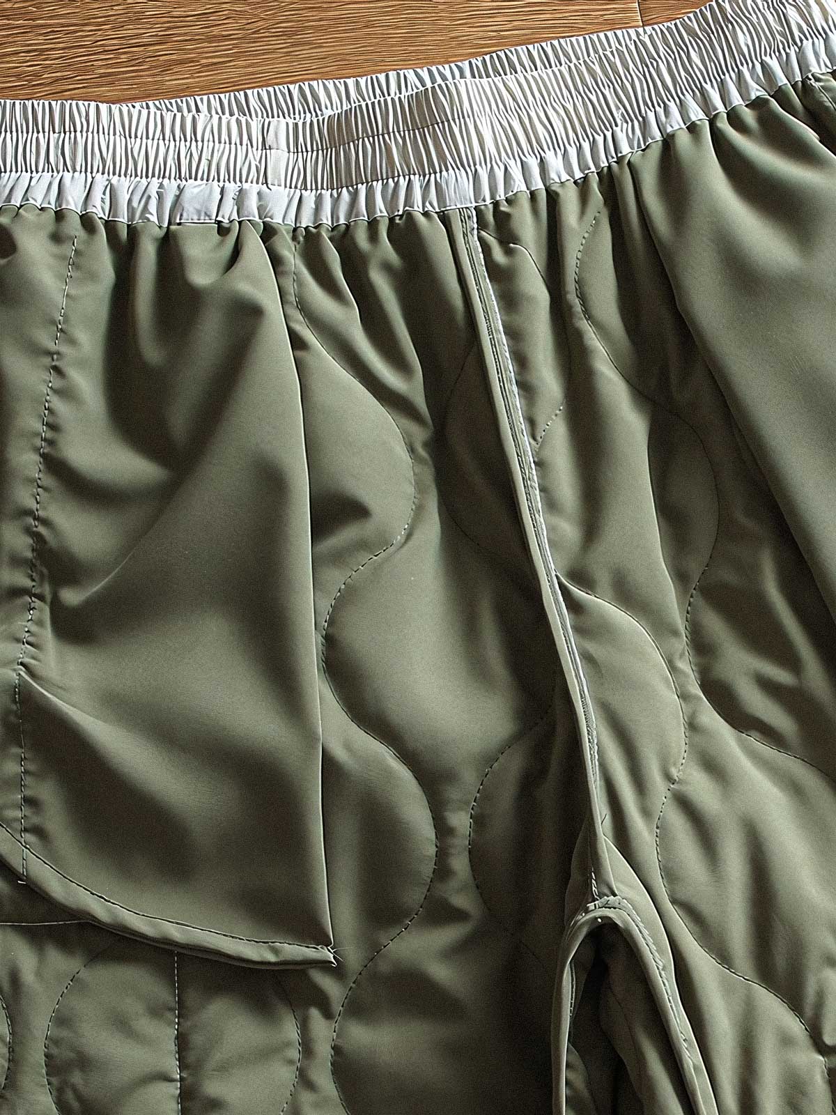 製品画像: 防風・防水機能を備えたキルティング中綿入り保温パンツ全体展示図。冬のアウトドア活動や寒い季節のカジュアルコーディネートに最適な高機能パンツ。
詳細画像: 高反発中綿が使用されたキルティングデザインのディテール。ウエストの伸縮性ゴムとドローコード、裾部分の調節機能で、機能性と快適さを兼ね備えたアウトドアパンツの特徴。