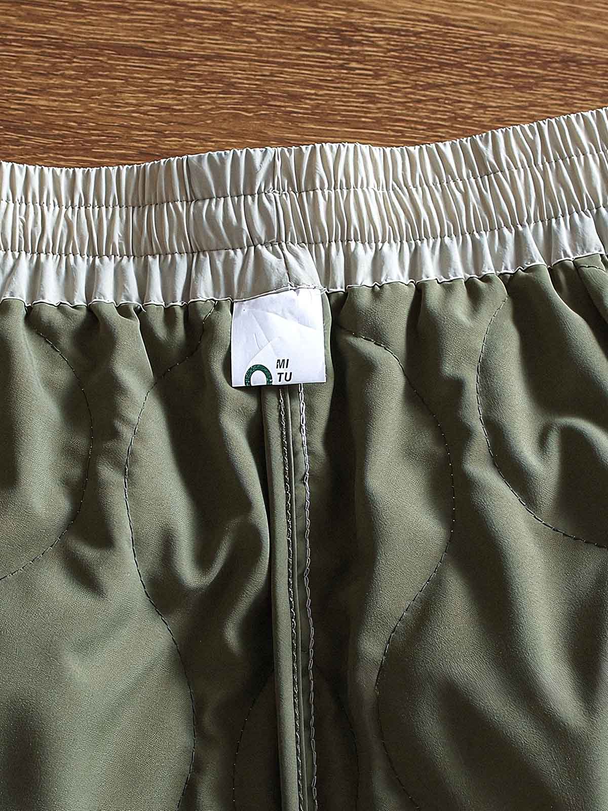 製品画像: 防風・防水機能を備えたキルティング中綿入り保温パンツ全体展示図。冬のアウトドア活動や寒い季節のカジュアルコーディネートに最適な高機能パンツ。
詳細画像: 高反発中綿が使用されたキルティングデザインのディテール。ウエストの伸縮性ゴムとドローコード、裾部分の調節機能で、機能性と快適さを兼ね備えたアウトドアパンツの特徴。