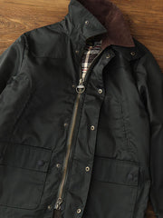 製品画像: コーデュロイカラーのコントラスト襟とオイルワックス加工が施されたハンティングジャケット。高密度梭織生地を使用し、耐久性とレトロ感を兼ね備えたデザイン。
詳細画像: チェック柄のキルティングライニングとスナップボタン付き風防襟のディテール。YKKのダブルヘッドラウンドリングジッパーと多機能ポケット配置が実用性を高めています。