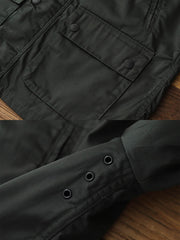 製品画像: コーデュロイカラーのコントラスト襟とオイルワックス加工が施されたハンティングジャケット。高密度梭織生地を使用し、耐久性とレトロ感を兼ね備えたデザイン。
詳細画像: チェック柄のキルティングライニングとスナップボタン付き風防襟のディテール。YKKのダブルヘッドラウンドリングジッパーと多機能ポケット配置が実用性を高めています。