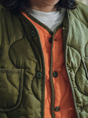 詳細画像: リバーシブルデザイン(オリーブグリーンとレスキューオレンジ)、袖口のリブ編みが冷気をシャットアウト。軽量でありながら優れた保温性を提供。
モデル画像: モデルが弧形キルティングインナーダウンジャケットを着用、ルーズフィットシルエットと防水性に優れた素材で、秋冬のレイヤードスタイルを演出。