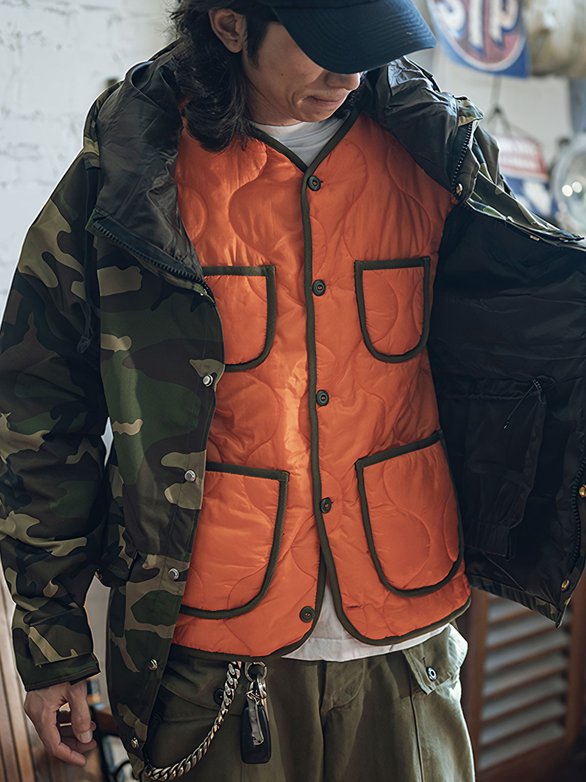 詳細画像: リバーシブルデザイン(オリーブグリーンとレスキューオレンジ)、袖口のリブ編みが冷気をシャットアウト。軽量でありながら優れた保温性を提供。
モデル画像: モデルが弧形キルティングインナーダウンジャケットを着用、ルーズフィットシルエットと防水性に優れた素材で、秋冬のレイヤードスタイルを演出。