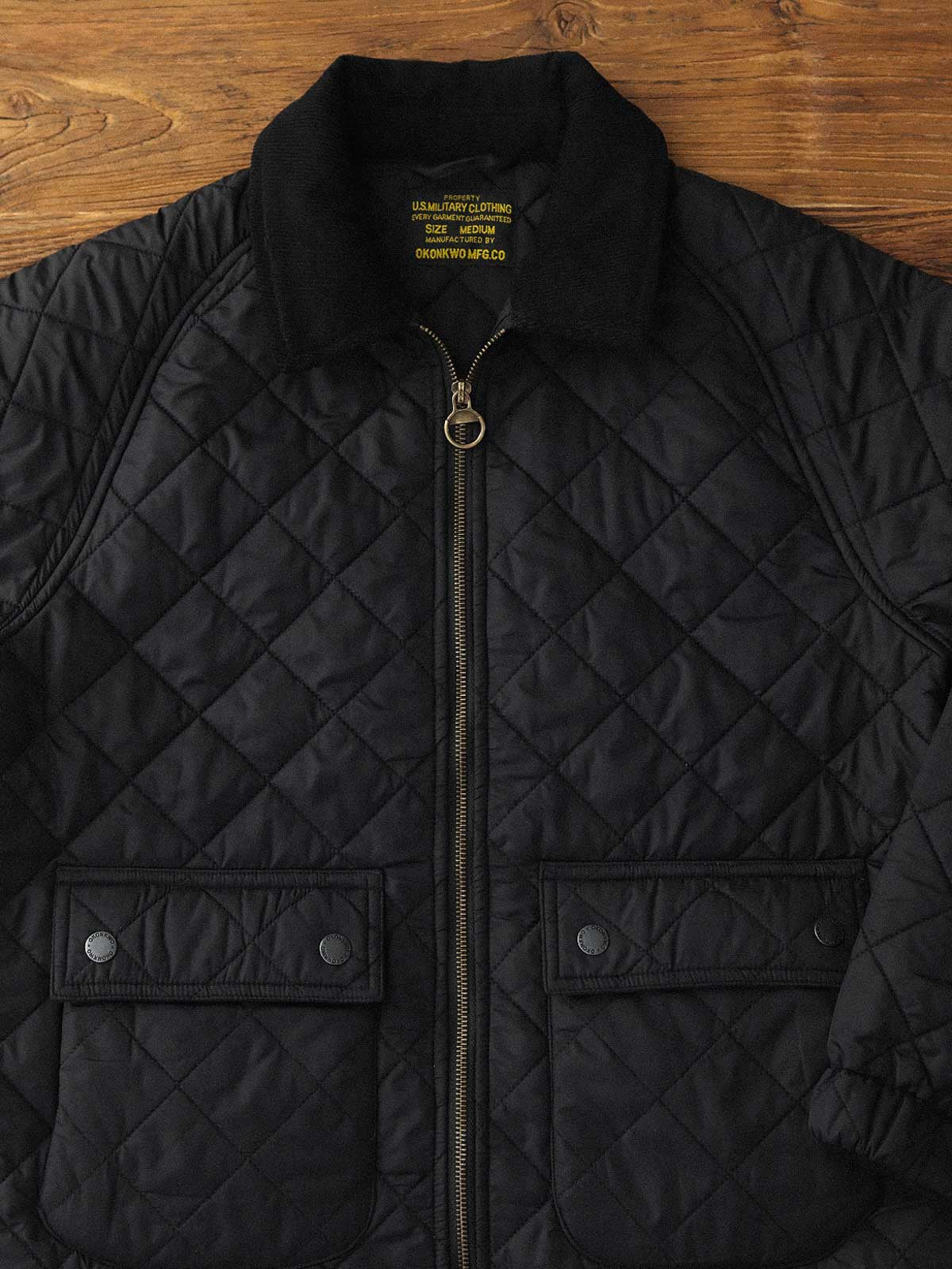 製品画像: ヴィンテージダイヤキルト中綿ジャケット正面展示図。クラシックなダイヤキルト縫製とコーデュロイ襟が特徴的なデザイン。軽量で暖かく、スリムなシルエット。
詳細画像: TALONの真鍮ジッパー、ラグランスリーブのディテール。大きなサイドポケットと斜めの隠しポケットが実用的なデザイン。