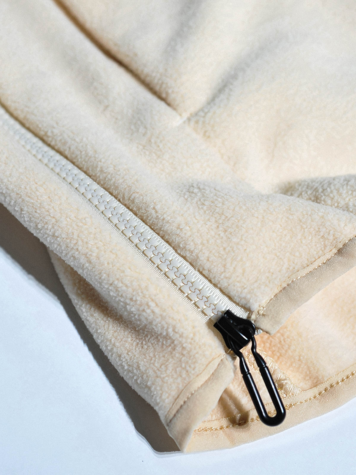 製品画像: サイドジップフリーススウェットの正面展示画像。ヴィンテージ風デザインが特徴で、ボタン付きネックデザインがクルーネックとノーカラーの2通りのスタイルを楽しめます。両面起毛の75Dフリース素材で、優れた保温性と通気性を実現し、アウトドアや日常使いに最適。
詳細画像: サイドジップのスリットデザイン、ラグランスリーブ、オーバーサイズのカットが特徴。伸縮性のあるリブ袖と裾で、動きやすさと快適さを提供。耐久性に優れ、毛玉ができにくいフリース素材を使用。