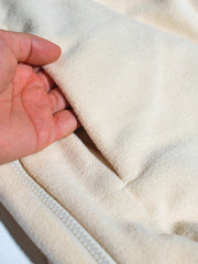 製品画像: サイドジップフリーススウェットの正面展示画像。ヴィンテージ風デザインが特徴で、ボタン付きネックデザインがクルーネックとノーカラーの2通りのスタイルを楽しめます。両面起毛の75Dフリース素材で、優れた保温性と通気性を実現し、アウトドアや日常使いに最適。
詳細画像: サイドジップのスリットデザイン、ラグランスリーブ、オーバーサイズのカットが特徴。伸縮性のあるリブ袖と裾で、動きやすさと快適さを提供。耐久性に優れ、毛玉ができにくいフリース素材を使用。