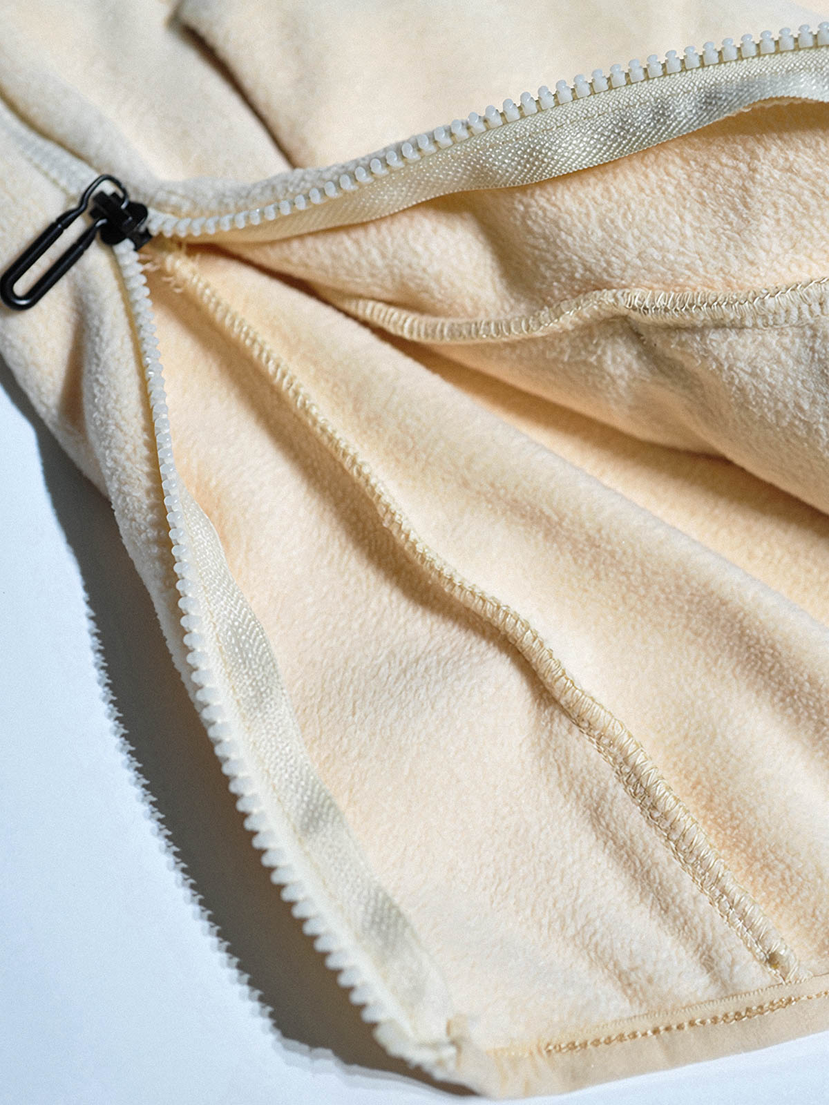 製品画像: サイドジップフリーススウェットの正面展示画像。ヴィンテージ風デザインが特徴で、ボタン付きネックデザインがクルーネックとノーカラーの2通りのスタイルを楽しめます。両面起毛の75Dフリース素材で、優れた保温性と通気性を実現し、アウトドアや日常使いに最適。
詳細画像: サイドジップのスリットデザイン、ラグランスリーブ、オーバーサイズのカットが特徴。伸縮性のあるリブ袖と裾で、動きやすさと快適さを提供。耐久性に優れ、毛玉ができにくいフリース素材を使用。