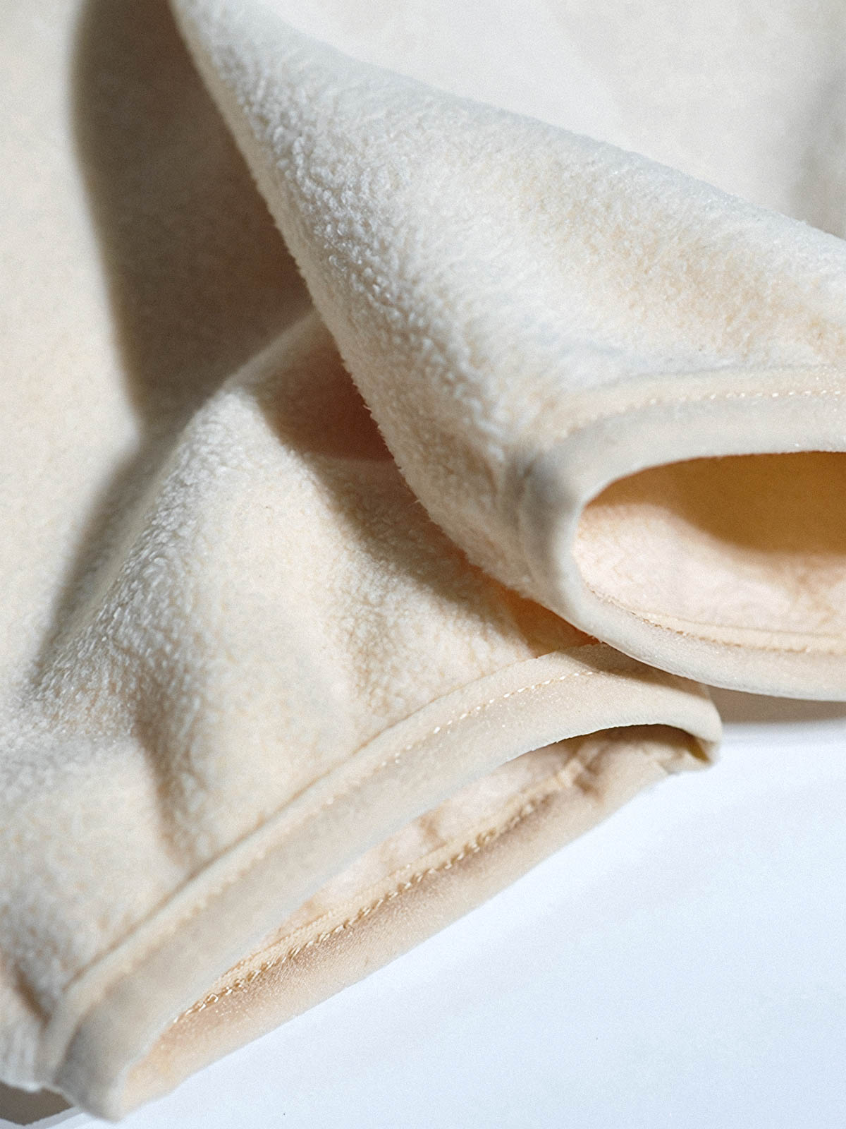 製品画像: サイドジップフリーススウェットの正面展示画像。ヴィンテージ風デザインが特徴で、ボタン付きネックデザインがクルーネックとノーカラーの2通りのスタイルを楽しめます。両面起毛の75Dフリース素材で、優れた保温性と通気性を実現し、アウトドアや日常使いに最適。
詳細画像: サイドジップのスリットデザイン、ラグランスリーブ、オーバーサイズのカットが特徴。伸縮性のあるリブ袖と裾で、動きやすさと快適さを提供。耐久性に優れ、毛玉ができにくいフリース素材を使用。