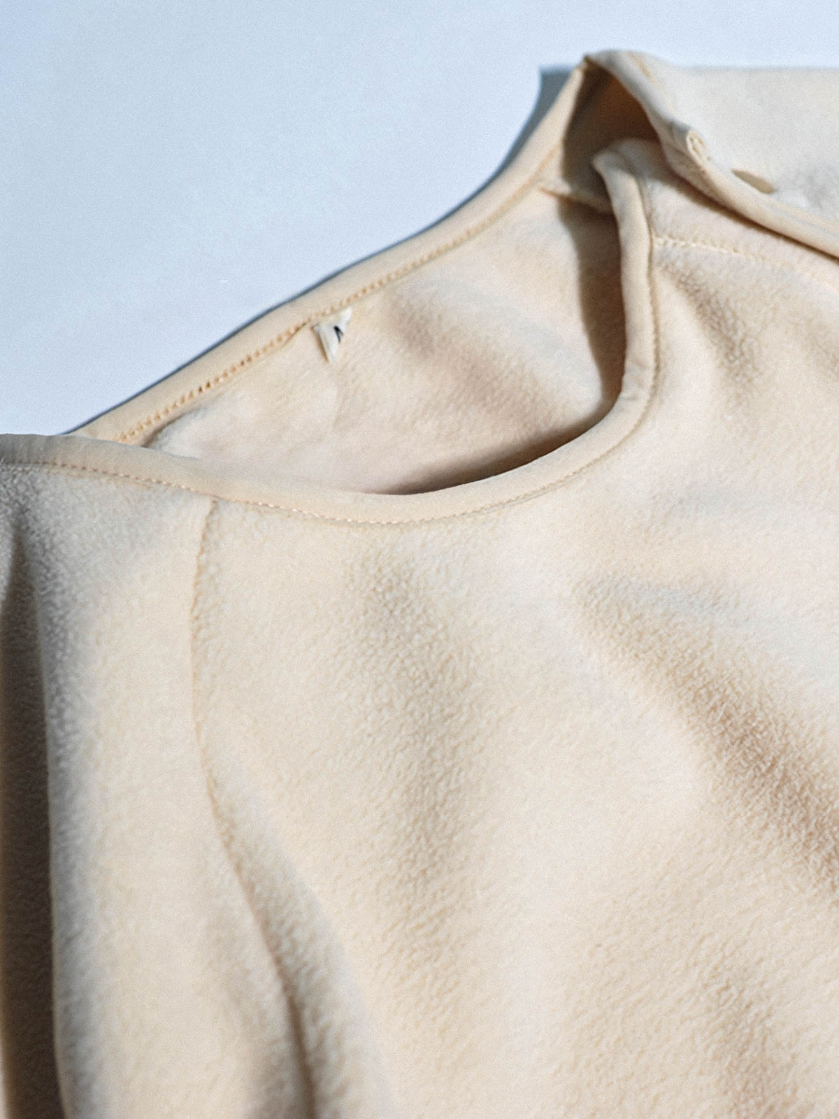 製品画像: サイドジップフリーススウェットの正面展示画像。ヴィンテージ風デザインが特徴で、ボタン付きネックデザインがクルーネックとノーカラーの2通りのスタイルを楽しめます。両面起毛の75Dフリース素材で、優れた保温性と通気性を実現し、アウトドアや日常使いに最適。
詳細画像: サイドジップのスリットデザイン、ラグランスリーブ、オーバーサイズのカットが特徴。伸縮性のあるリブ袖と裾で、動きやすさと快適さを提供。耐久性に優れ、毛玉ができにくいフリース素材を使用。