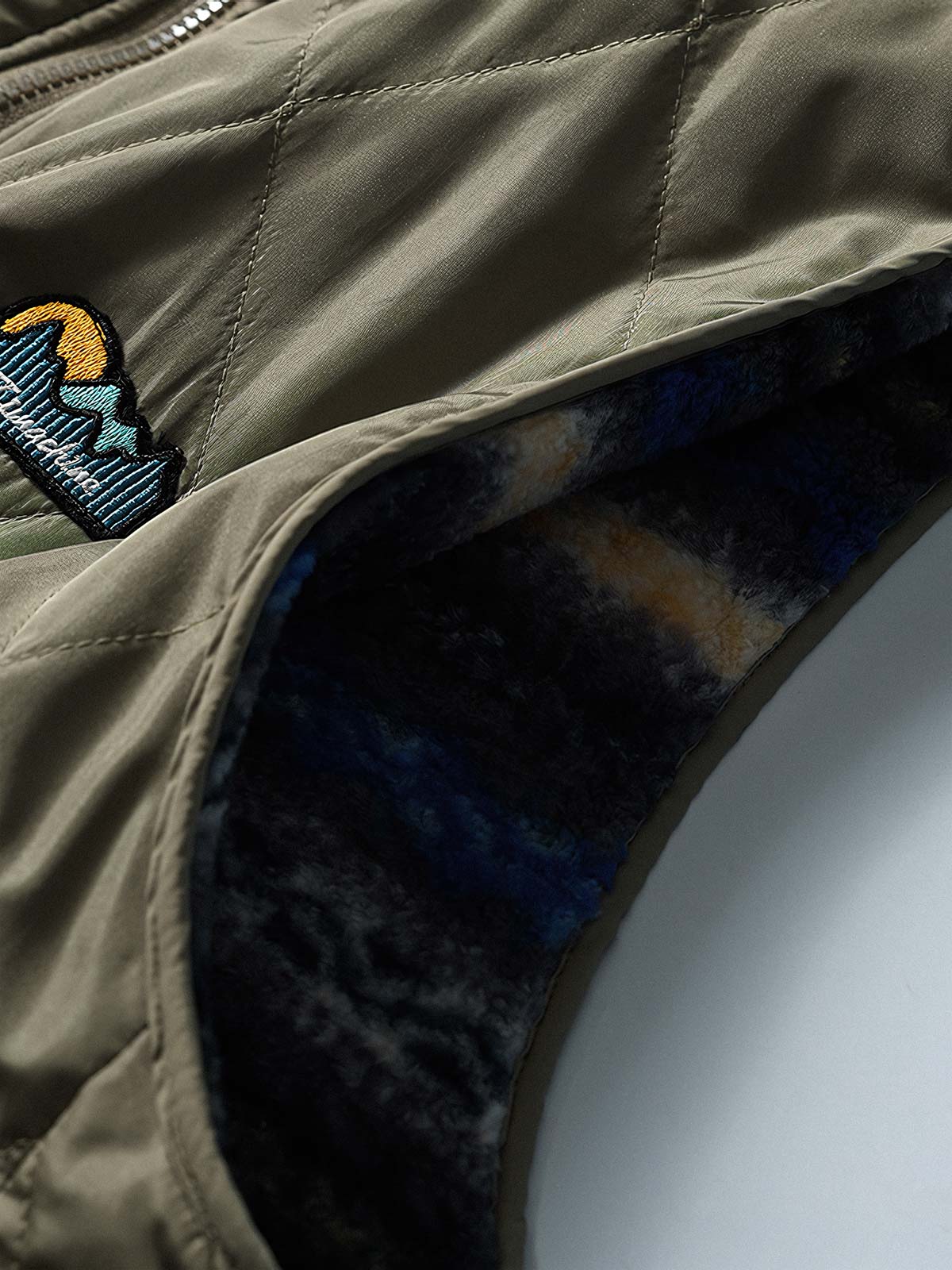 製品画像: リバーシブルデザインのラムファーワークベスト正面展示画像、民族風スタイルで暖かさと快適さを提供するユニセックスアイテム。
詳細画像: ベストの内側に施されたラムファーのディテールアップ、リバーシブルデザインによるコーディネートの幅が広がる特徴。