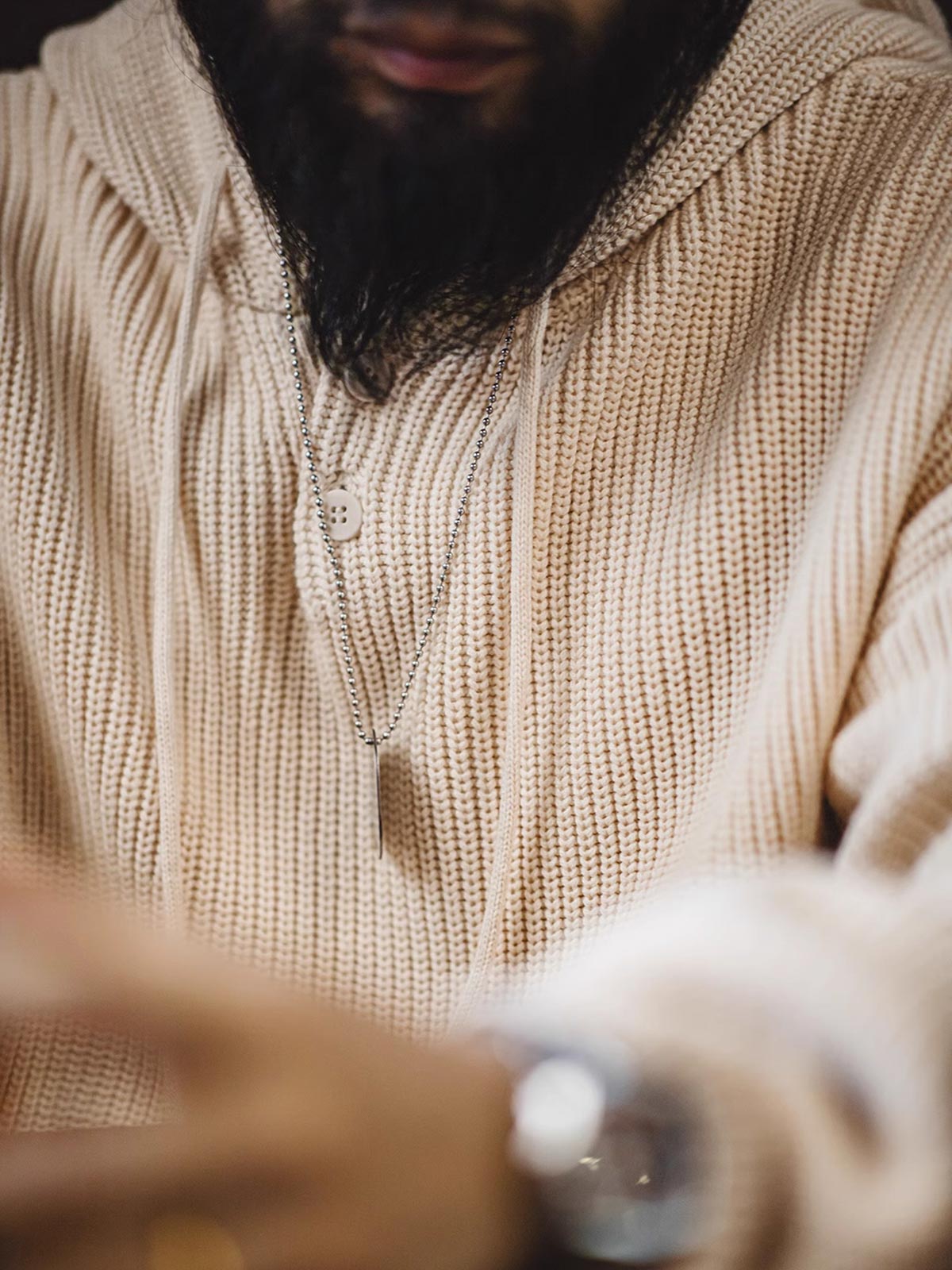 詳細画像:
縦じまのニット素材、ヘンリーネックのY字デザイン、フードとドローコード付き、リブディテールでフィット感強調、胸元のカスタムヴィンテージラベル
モデル画像:
モデルがヘンリーネック縦じまニットパーカーを着用、リラックスしたカジュアルスタイルでワイドパンツやデニムと完璧にコーディネート