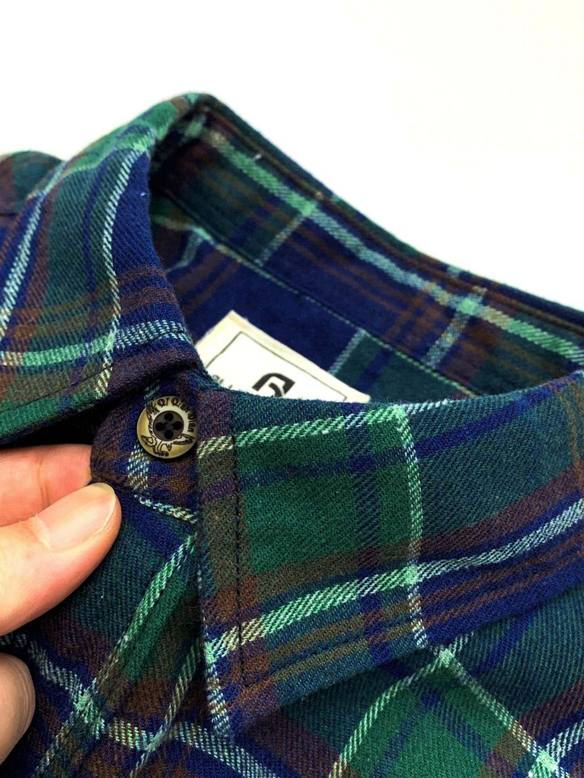 製品画像: 100%コットンツイル起毛素材のヴィンテージ風イギリス風チェック柄シャツ。秋冬に最適な柔らかな肌触りと優れた保温性。
詳細画像: ゆったりとしたシルエットのチェック柄シャツ。デニムやカジュアルパンツとの相性が良く、重ね着にも最適。